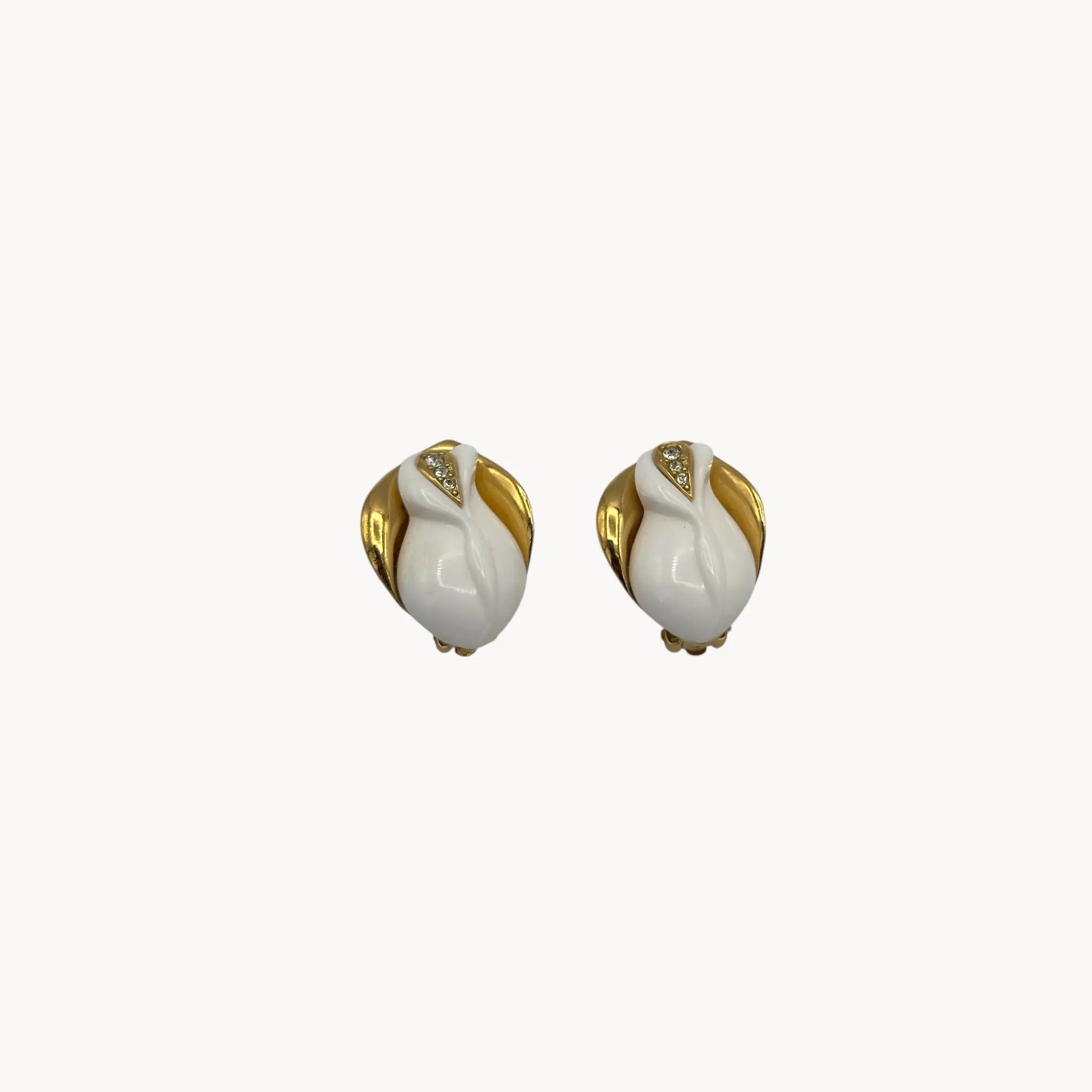 Close up of Kenneth Jay Lane for Avon white enamel rose clip-on earrings with gold and crystal accents