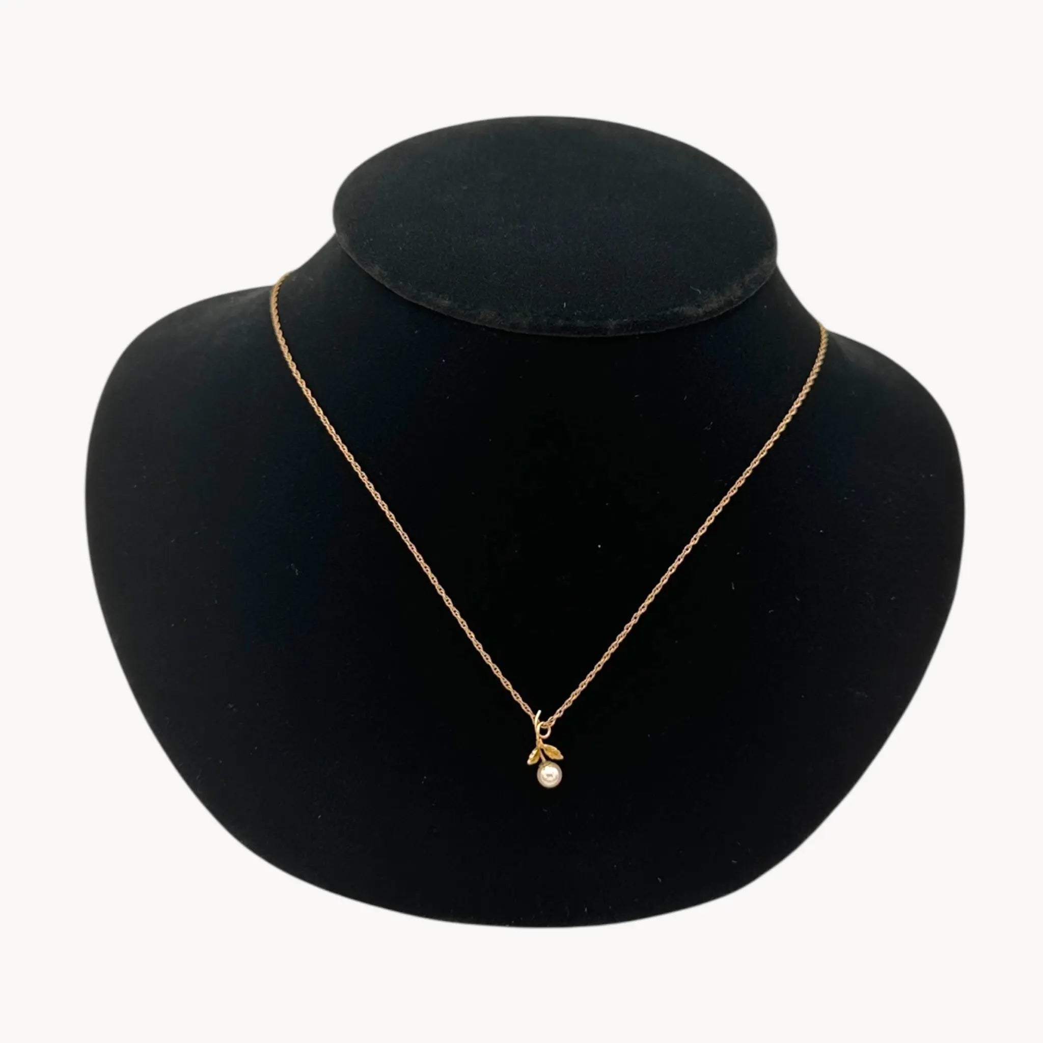 Close up of Krementz dainty gold flower pendant necklace with pearl center.