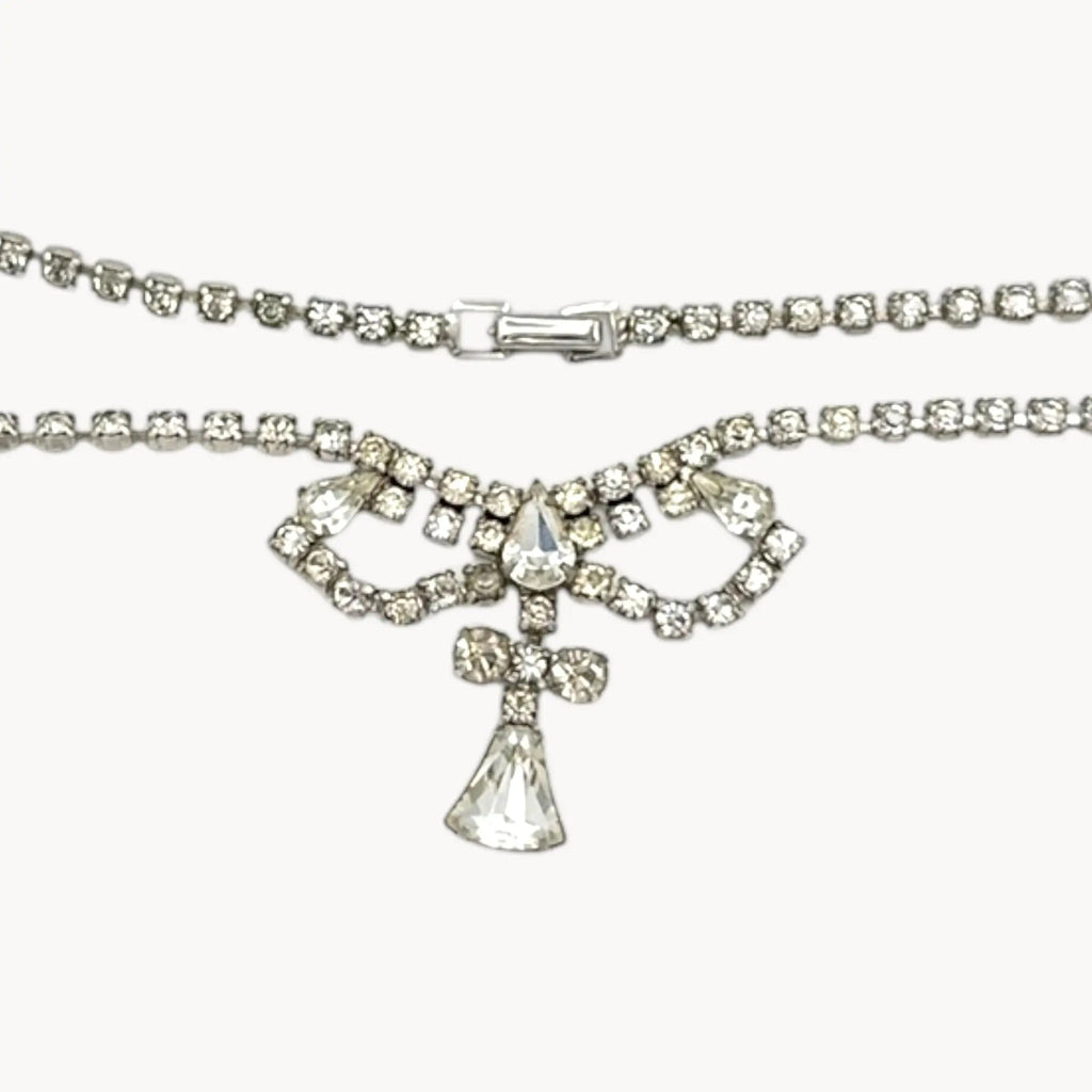 Close up view 1950s Leo Glass rhinestone necklace with bow centerpiece and teardrop pendant, vintage mid-century bridal jewelry.