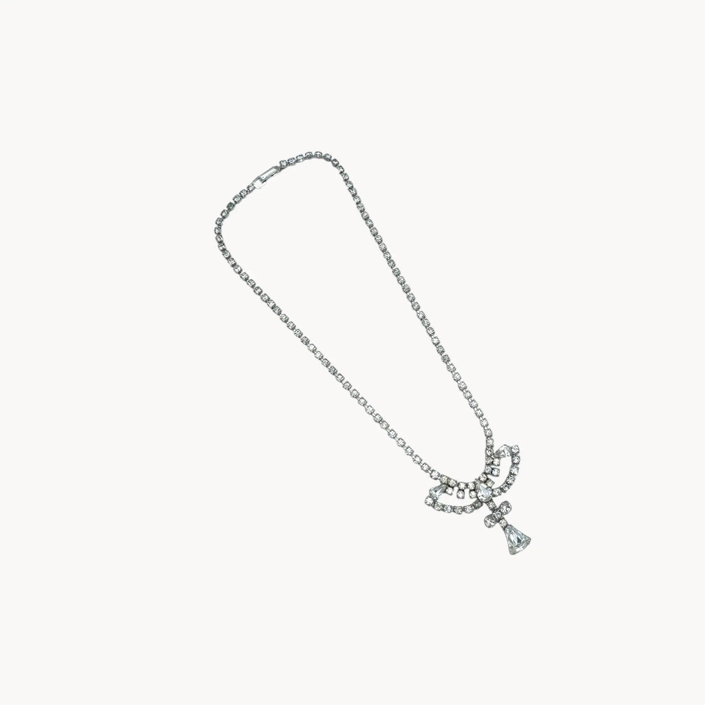 On white view 1950s Leo Glass rhinestone necklace with bow centerpiece and teardrop pendant, vintage mid-century bridal jewelry.