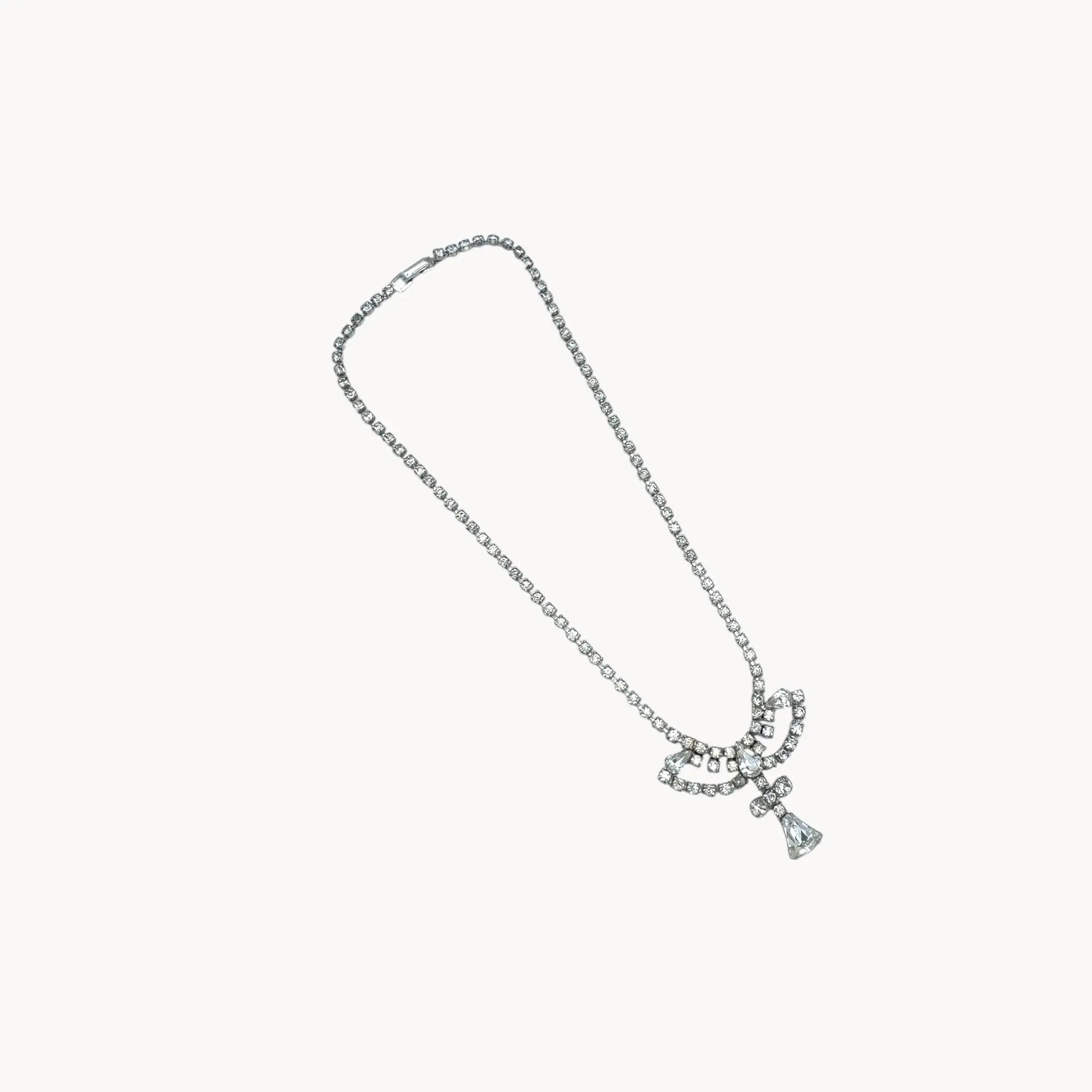 On white view 1950s Leo Glass rhinestone necklace with bow centerpiece and teardrop pendant, vintage mid-century bridal jewelry.