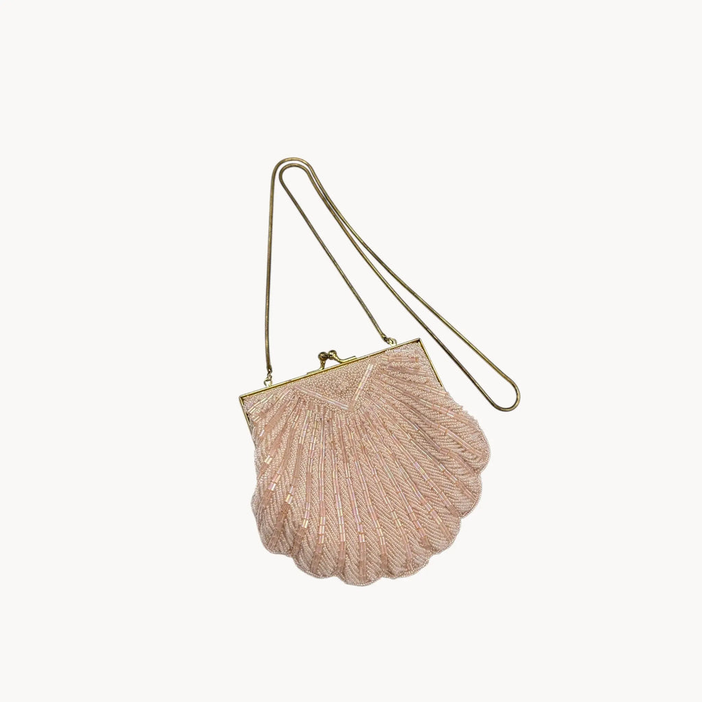 Magid iridescent light pink beaded clamshell crossbody handbag with gold chain on white background.