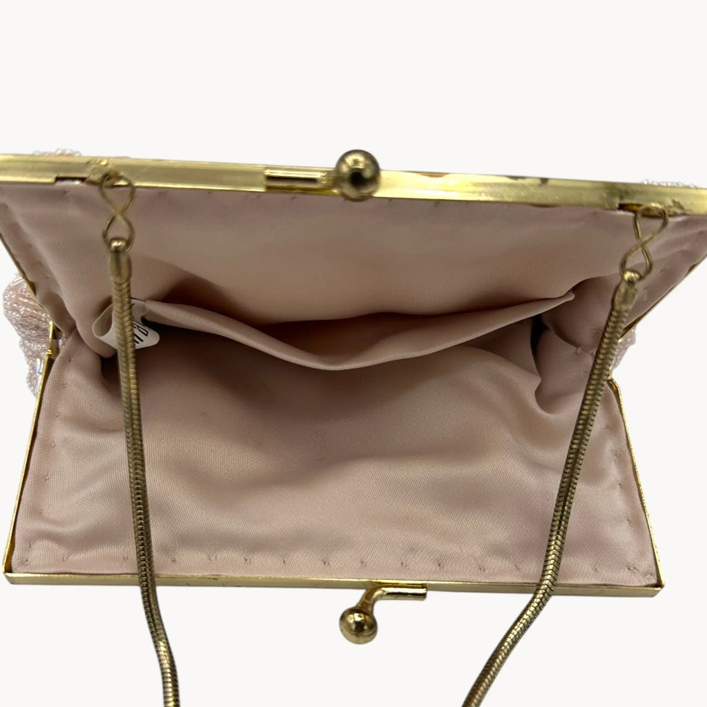 Inside view of Magid iridescent light pink beaded clamshell crossbody handbag with gold chain on white background.