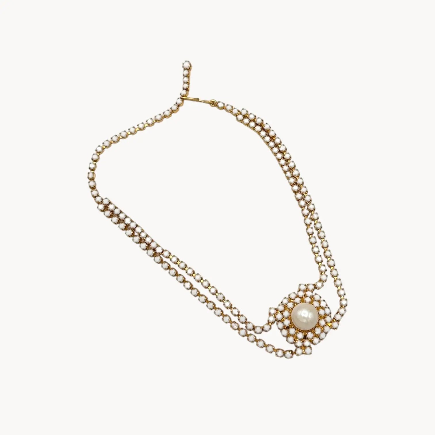 Against white background Mid-century milk glass rhinestone bridal choker necklace with central pearl medallion.