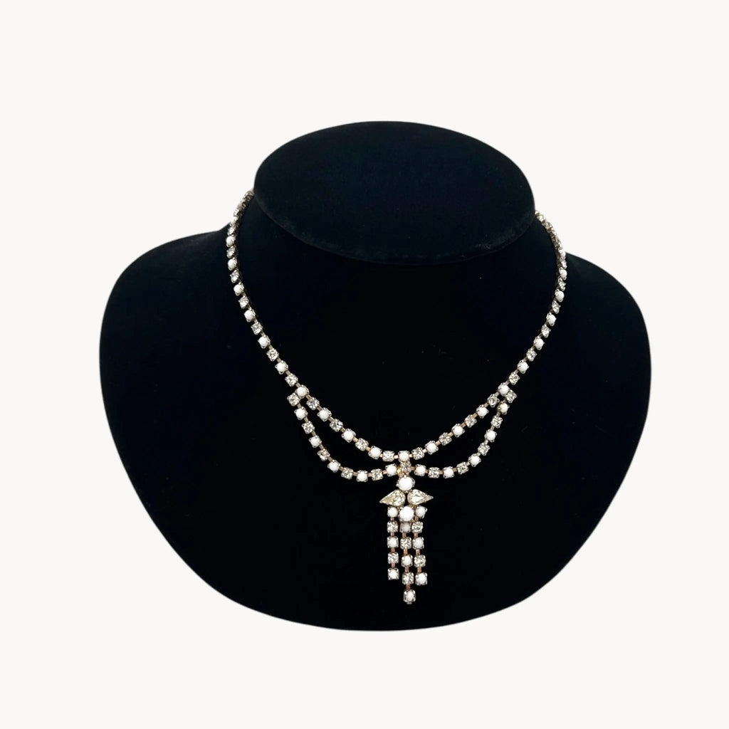 Close up view of Vintage mid-century rhinestone and milk glass draped necklace with pendant drop.
