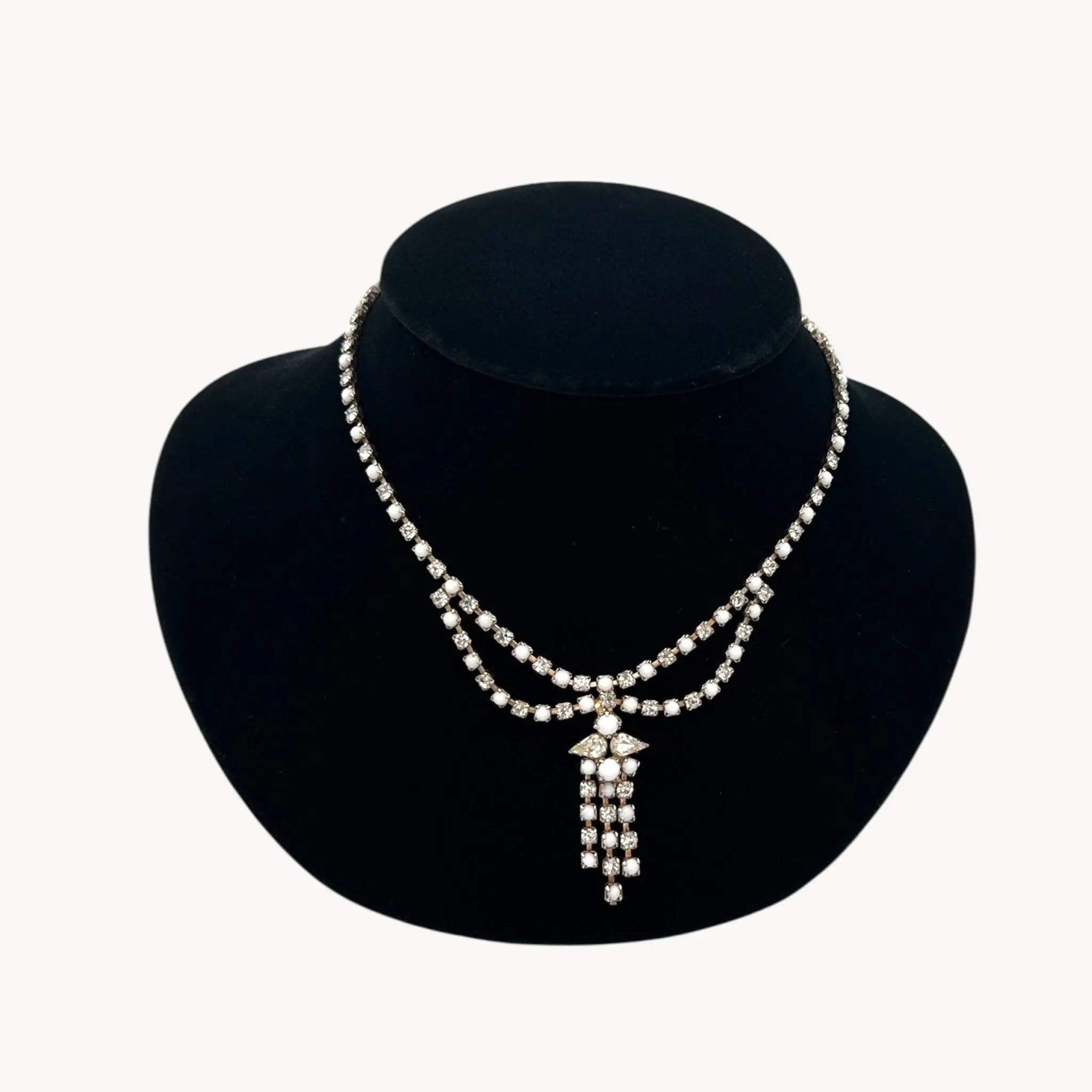 Close up view of Vintage mid-century rhinestone and milk glass draped necklace with pendant drop.