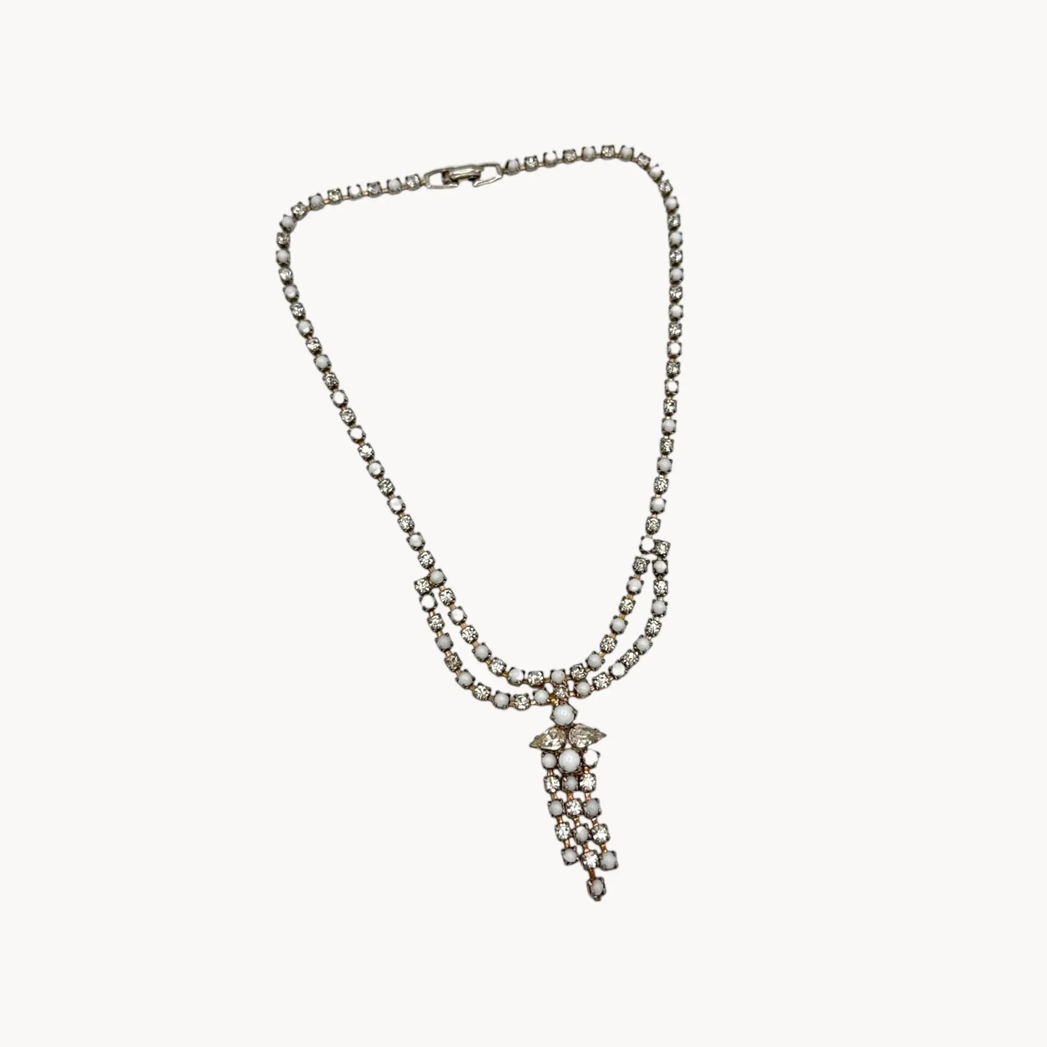 On white background Vintage mid-century rhinestone and milk glass draped necklace with pendant drop.