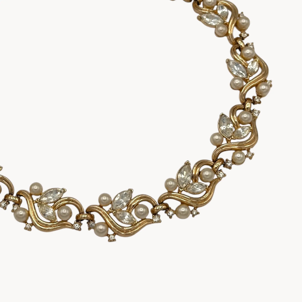 Close up view on white background of Midcentury gold floral rhinestone necklace with faux pearls.