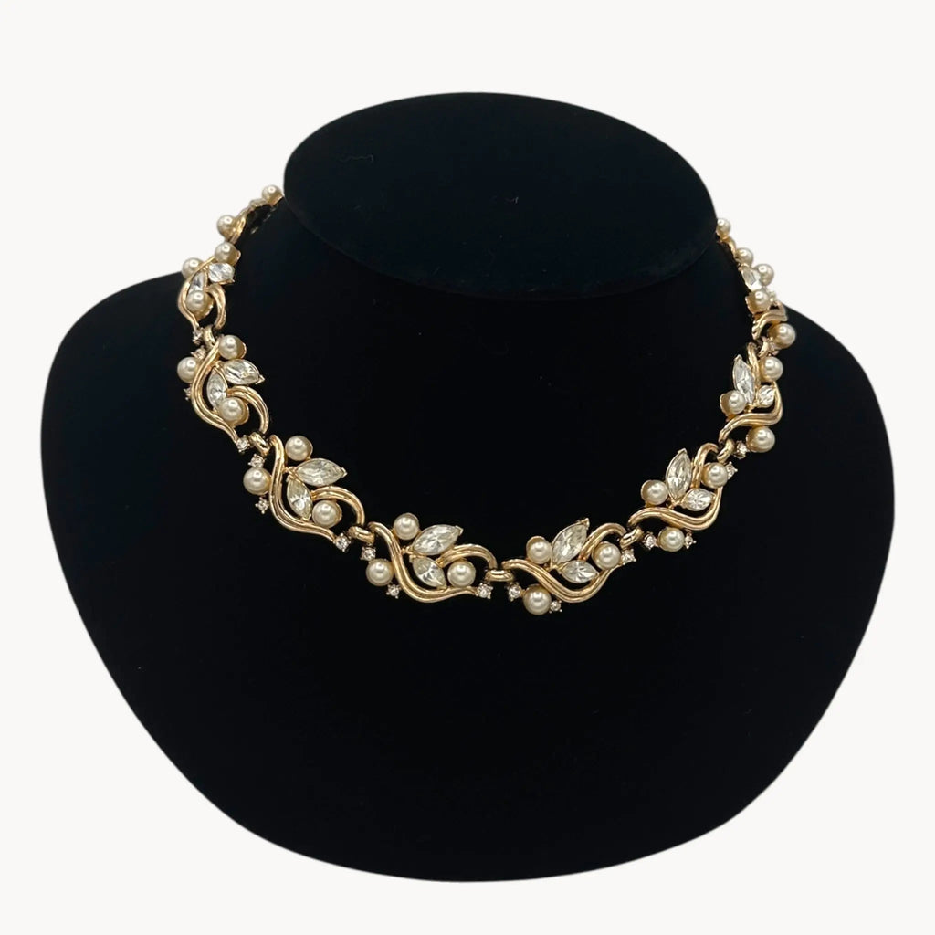 Close up view of Midcentury gold floral rhinestone necklace with faux pearls.