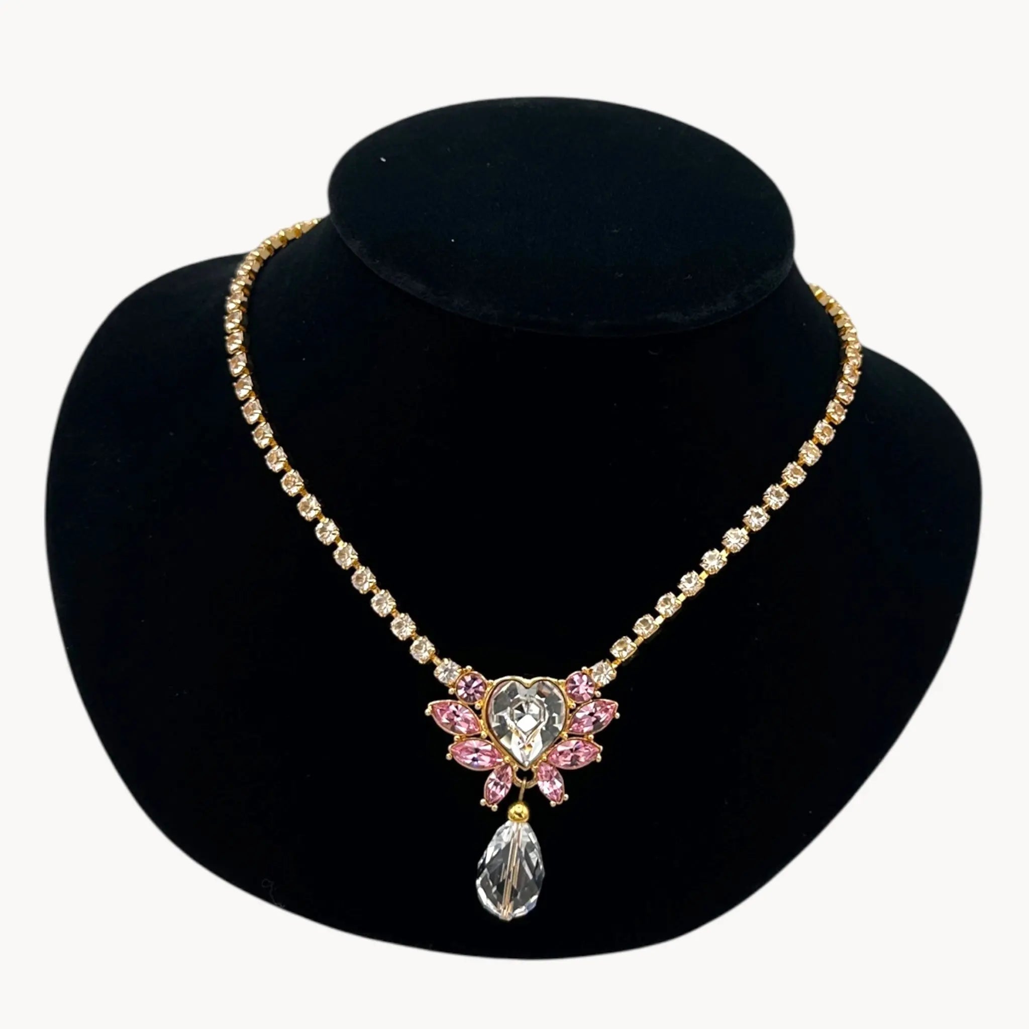 Close up of pendant of Vintage Monet gold necklace and clip-on earring set with clear heart and pink rhinestones.
