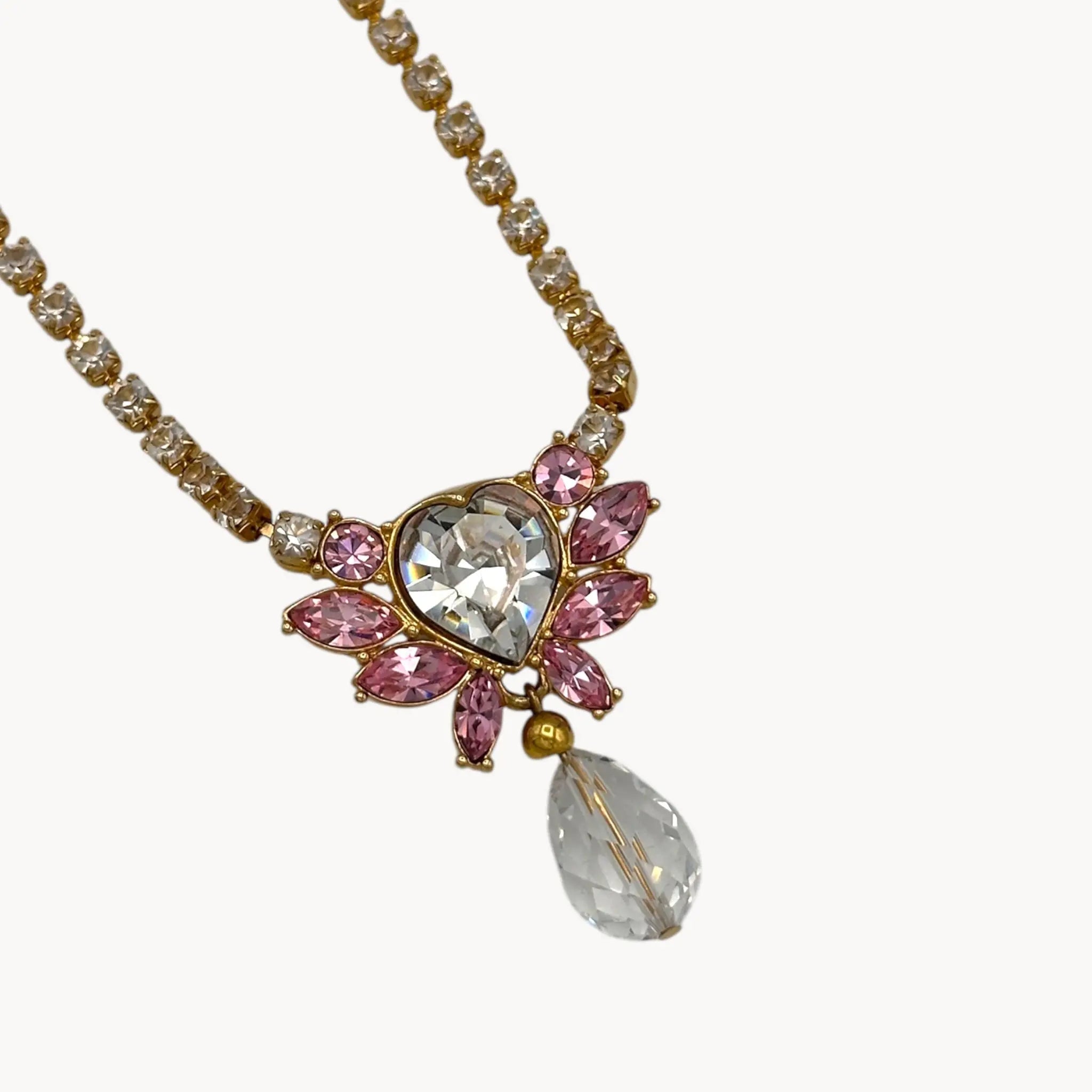 Close up of pendant of Vintage Monet gold necklace and clip-on earring set with clear heart and pink rhinestones.