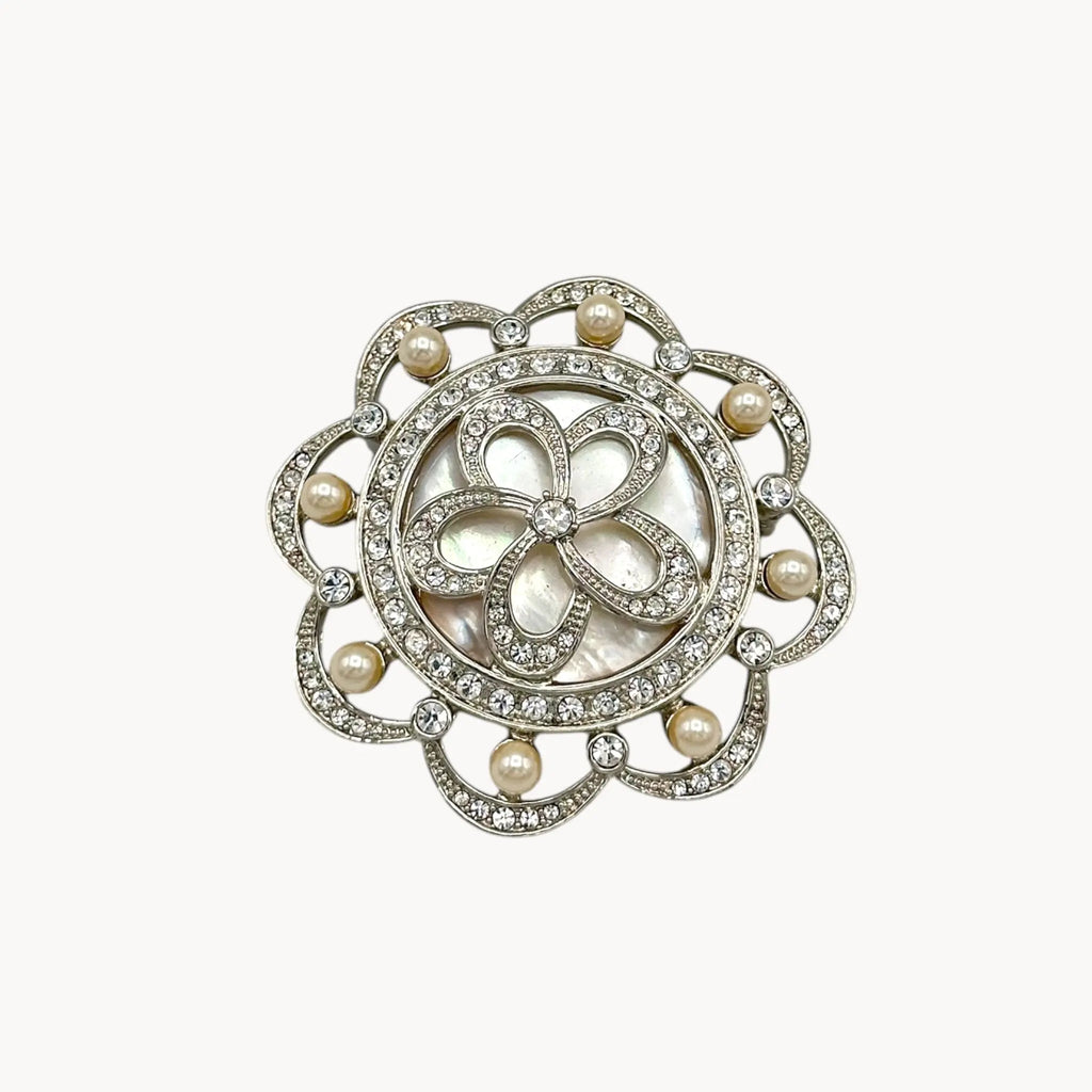 Close up view of Monet vintage silver tone brooch with rhinestones and faux pearls in floral design, elegant bridal jewelry piece on white background.