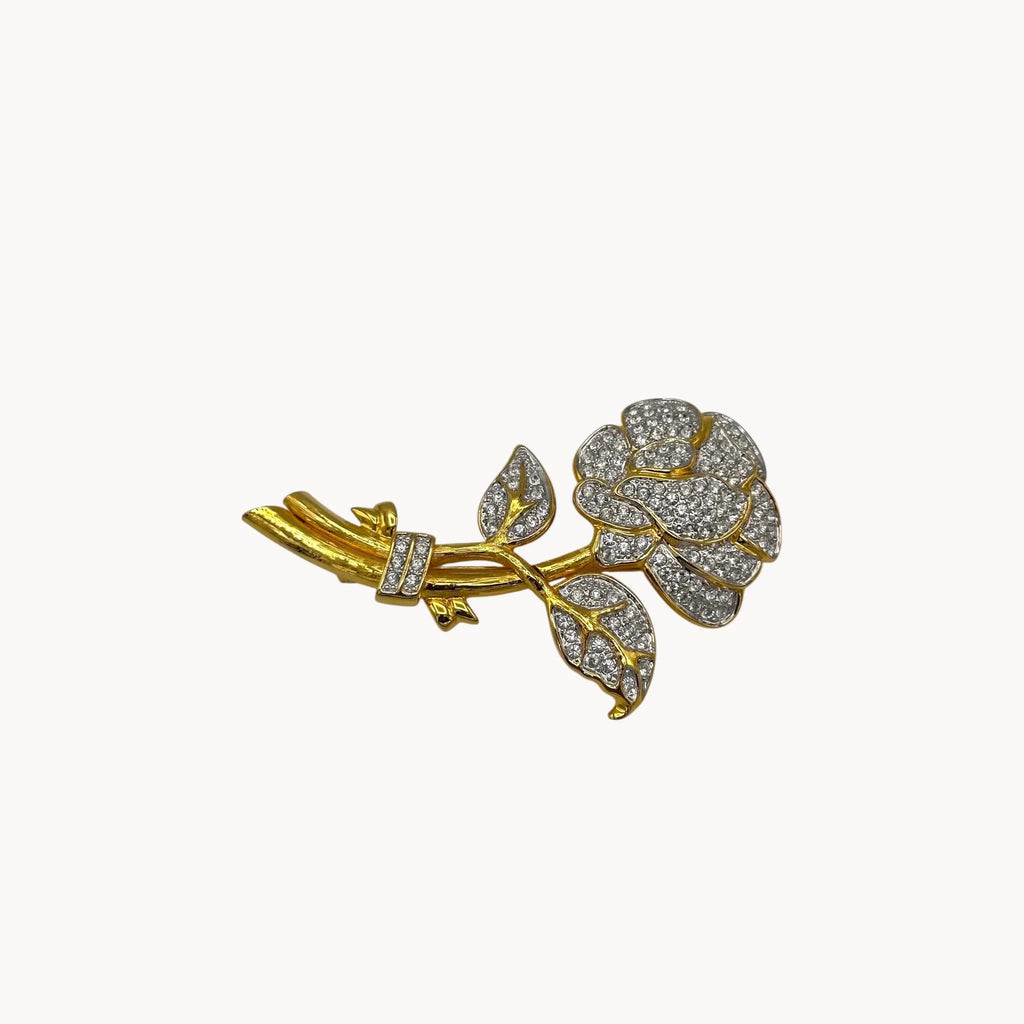 Side view of Nolan Miller gold and rhinestone flower brooch with pavé crystal accents