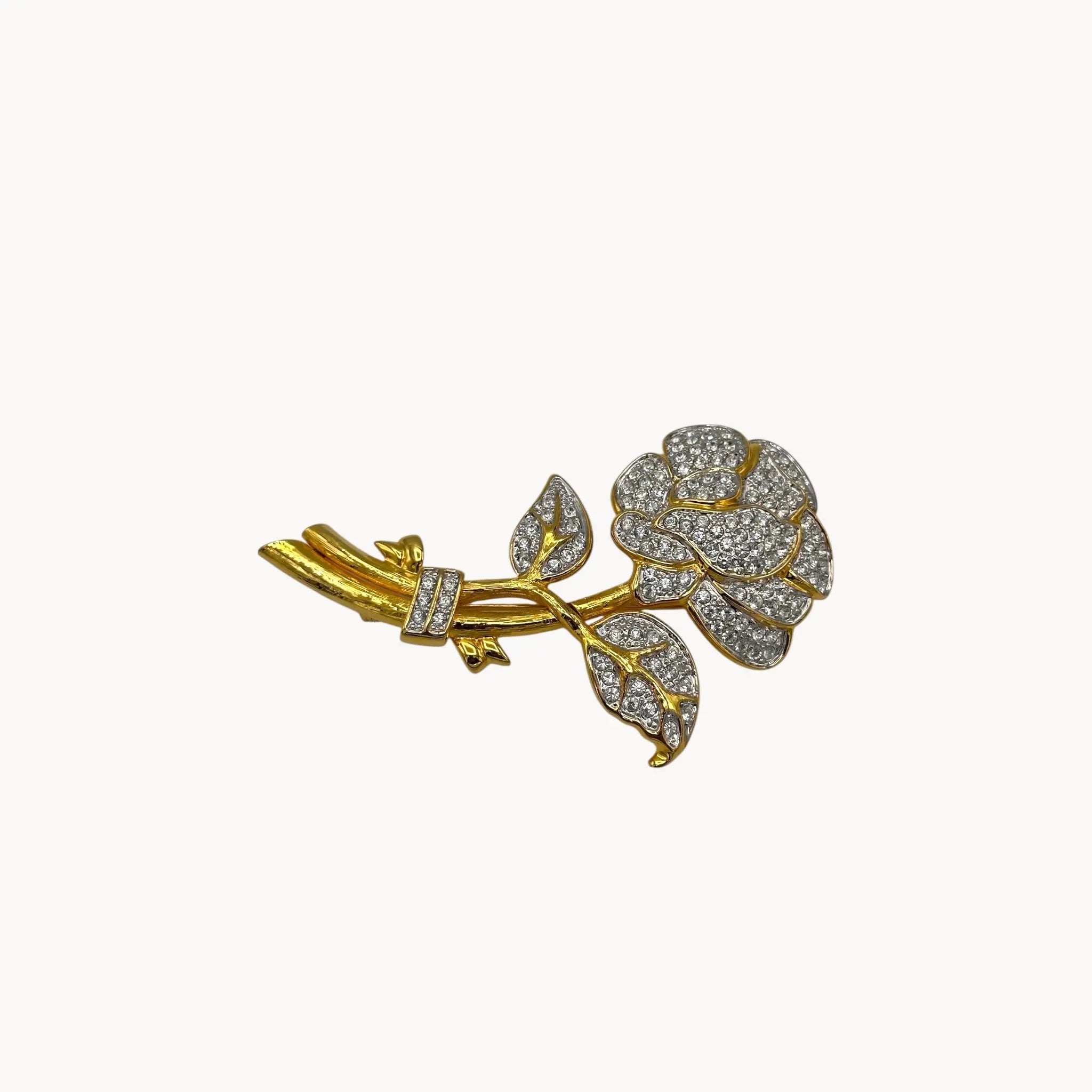 Side view of Nolan Miller gold and rhinestone flower brooch with pavé crystal accents