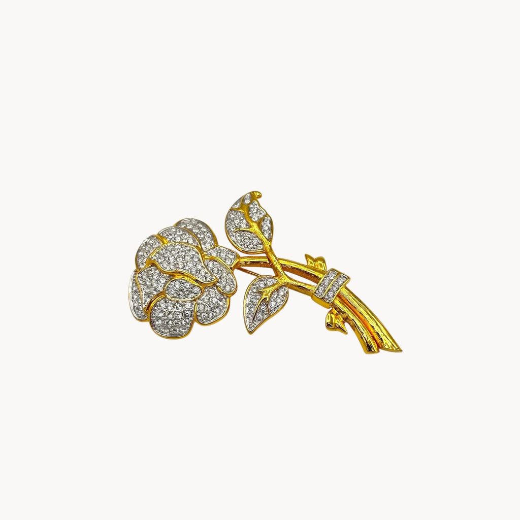 Close up view of Nolan Miller gold and rhinestone flower brooch with pavé crystal accents