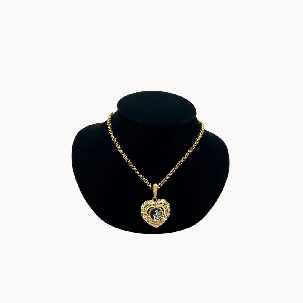 Nolan Miller gold-tone heart pendant necklace with clear rhinestones on long chain on black bust.