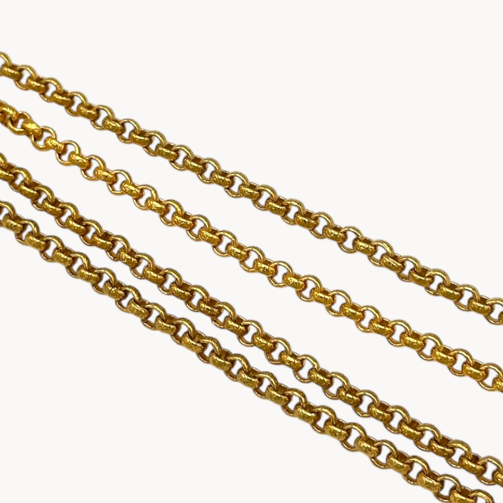 Close up of chain of Nolan Miller gold-tone heart pendant necklace with clear rhinestones on long chain on white background.