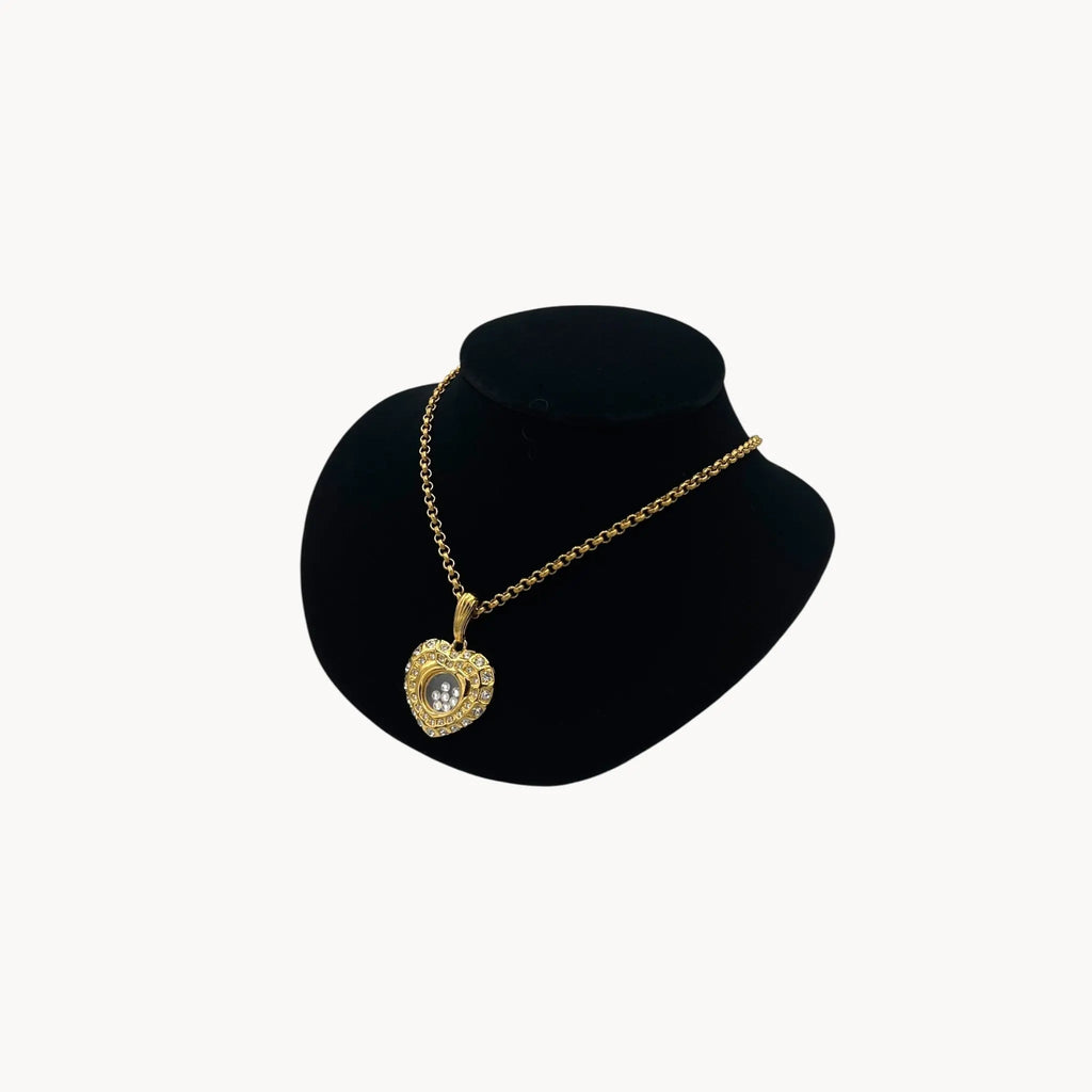 Side view of Nolan Miller gold-tone heart pendant necklace with clear rhinestones on long chain on black bust.