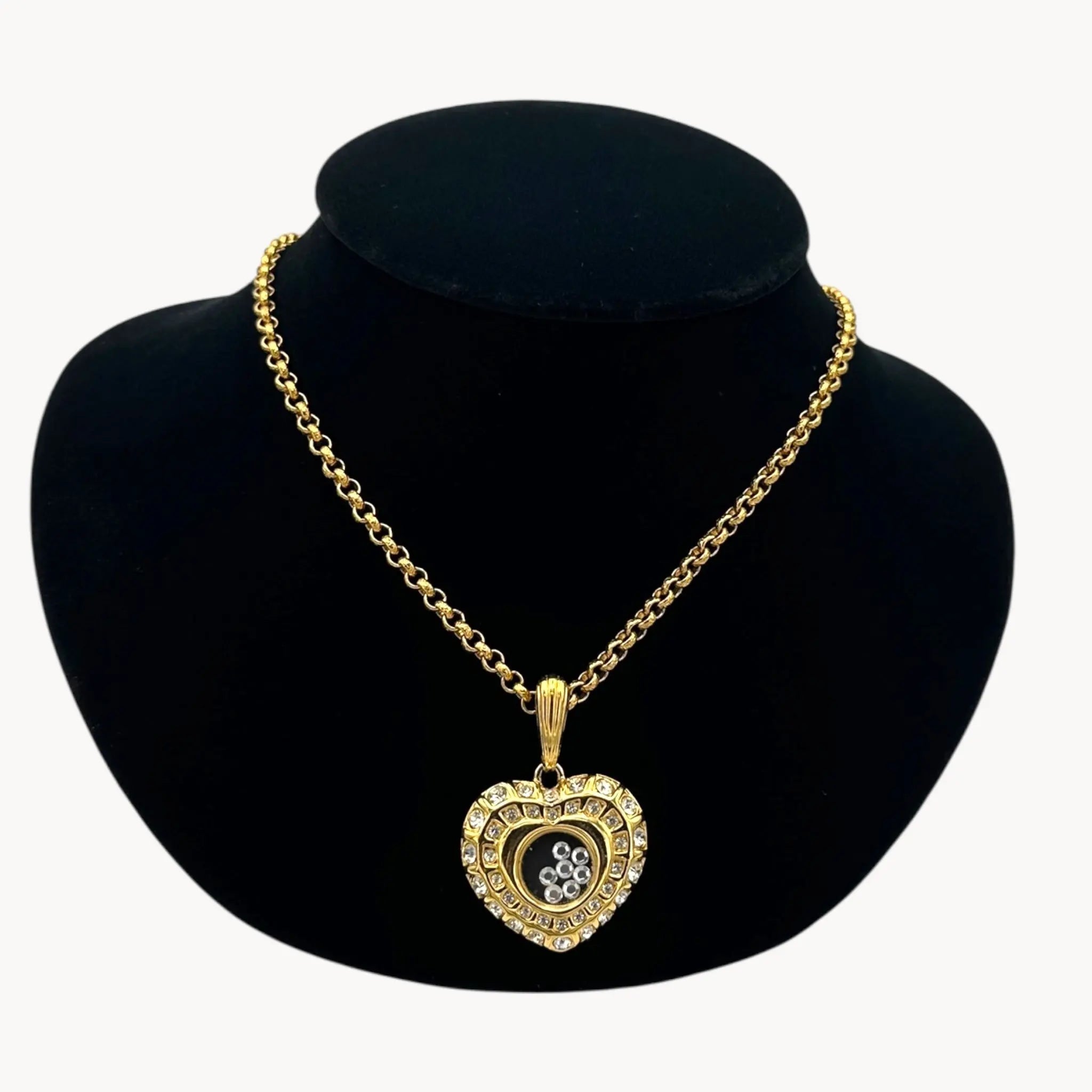 Close up view of Nolan Miller gold-tone heart pendant necklace with clear rhinestones on long chain on black bust.