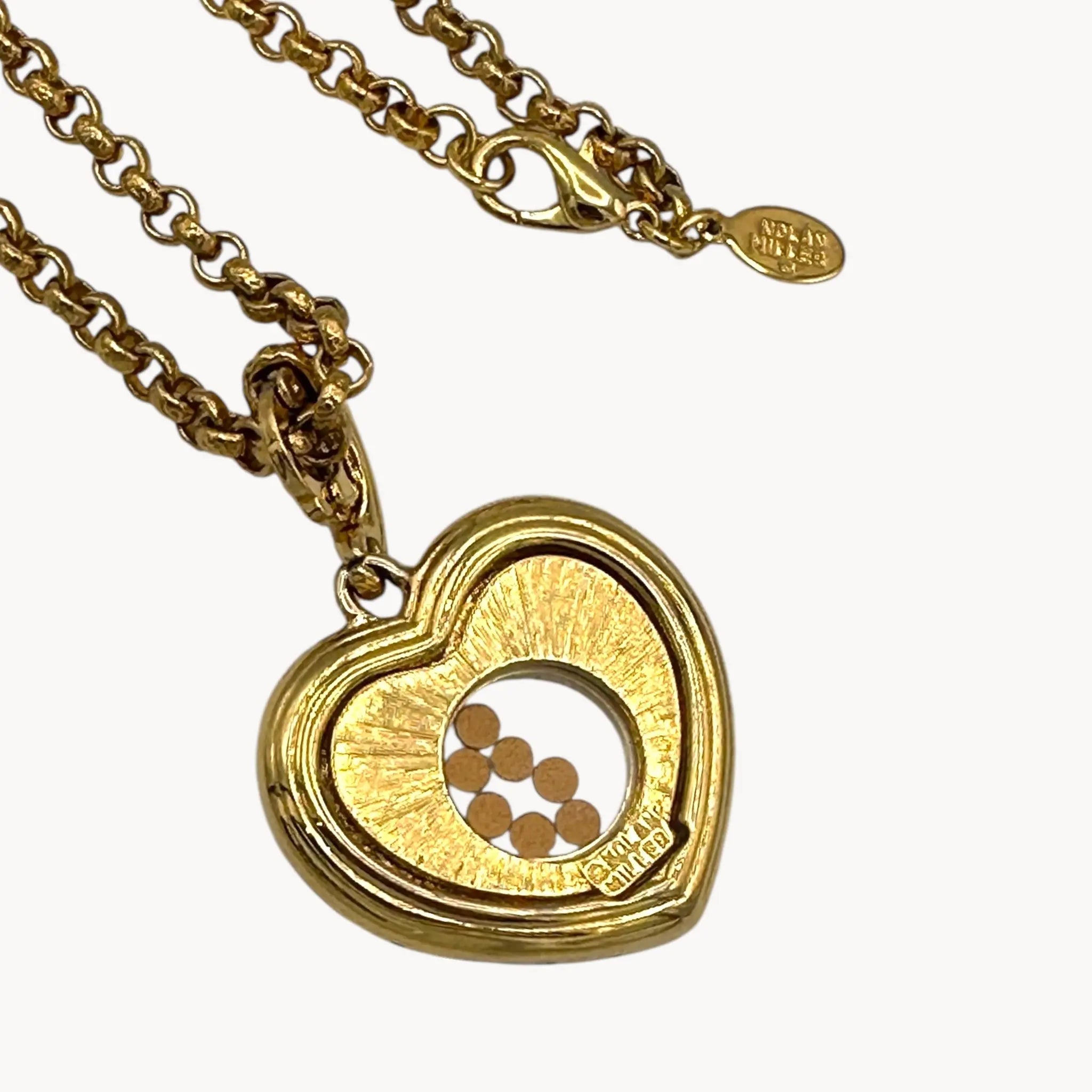 Back view of pendant of Nolan Miller gold-tone heart pendant necklace with clear rhinestones on long chain on white background.