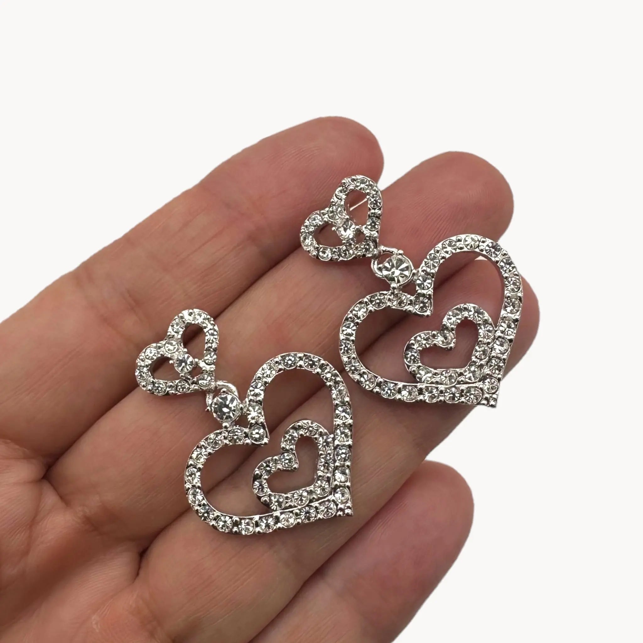 Scale picture Vintage Nolan Miller rhinestone heart dangle pierced earrings with double open-heart design.