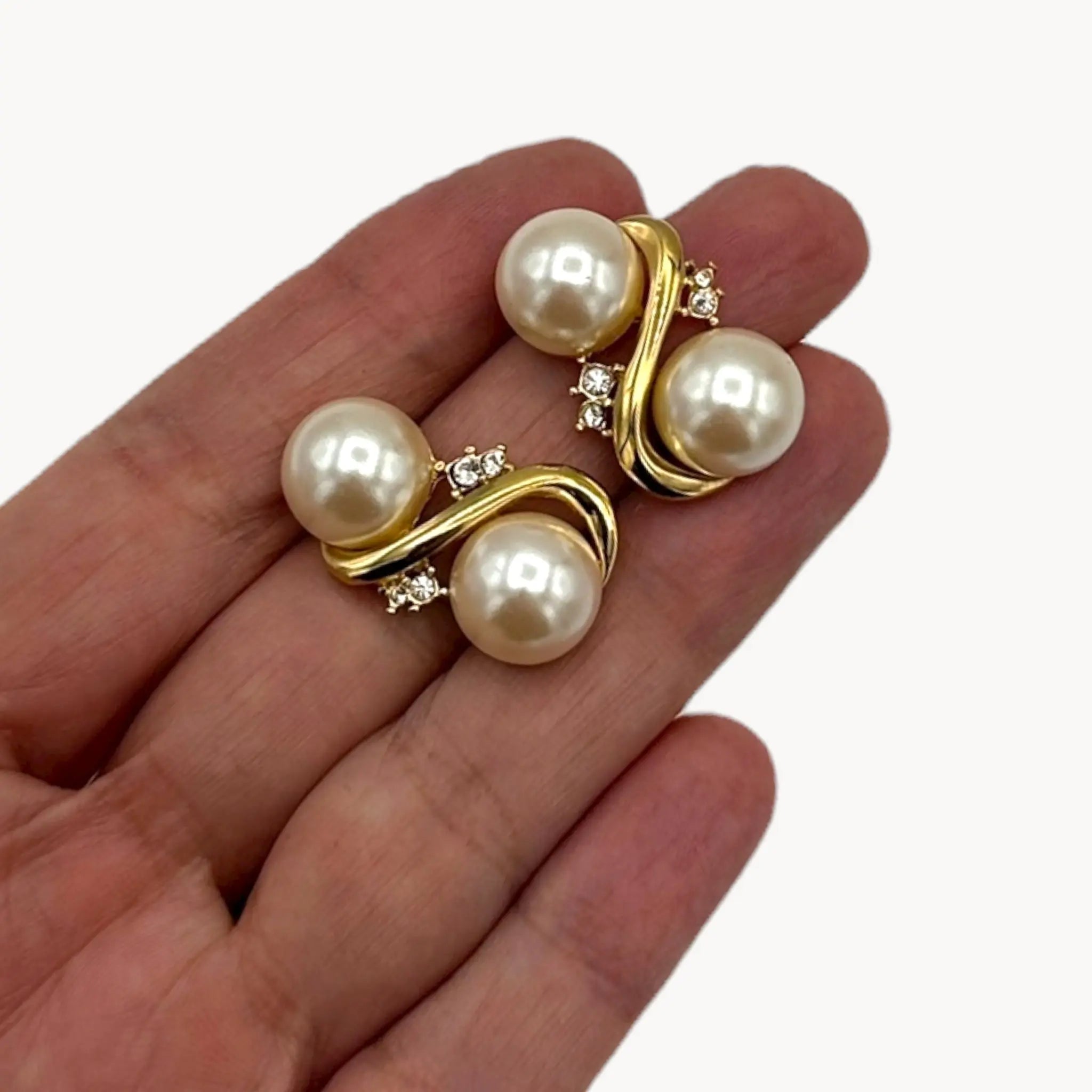 Shown on hand, Richelieu vintage gold tone pierced earrings with double faux pearls and rhinestone accents, elegant 1980s bridal jewelry shown on white background.