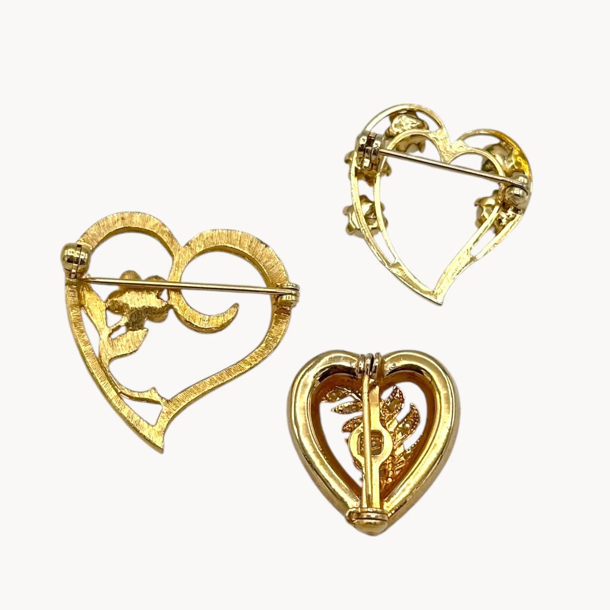 Back of Set of three vintage gold heart brooches with pearls and rhinestones, mid-century scatter pins on white background.