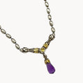 Close up view of pendant of Sterling silver and 14K yellow gold necklace with amethyst teardrop pendant on white background.