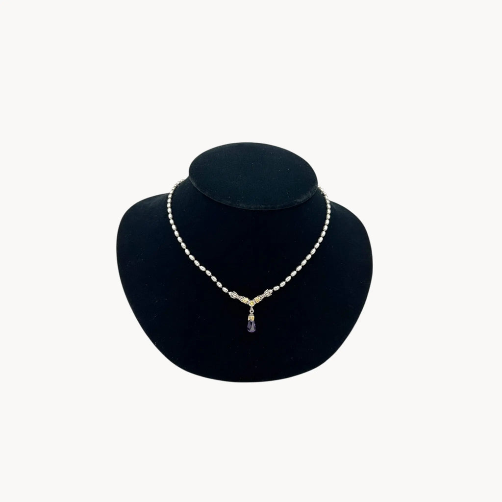 Sterling silver and 14K yellow gold necklace with amethyst teardrop pendant on black bust.