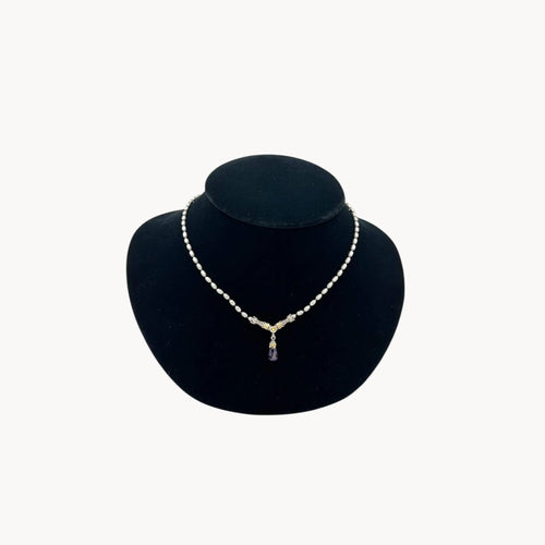 Sterling silver and 14K yellow gold necklace with amethyst teardrop pendant on black bust.