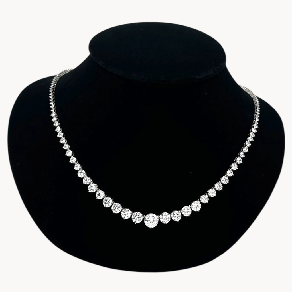 Close up view of Sterling silver rhodium-plated graduated tennis necklace with round-cut stones on black bust.