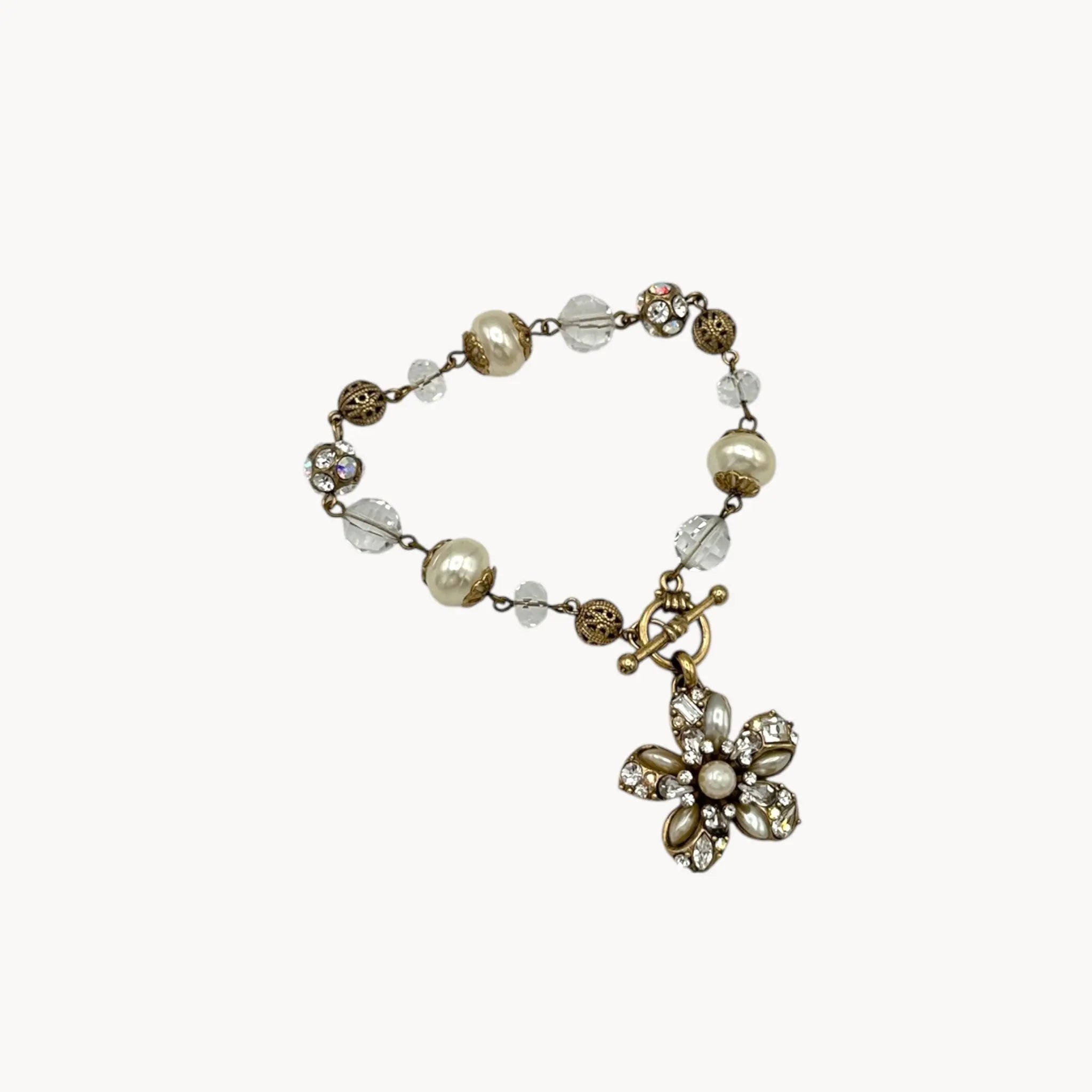 Flat lay against white of Sweet Romance floral charm bracelet with pearls and rhinestones