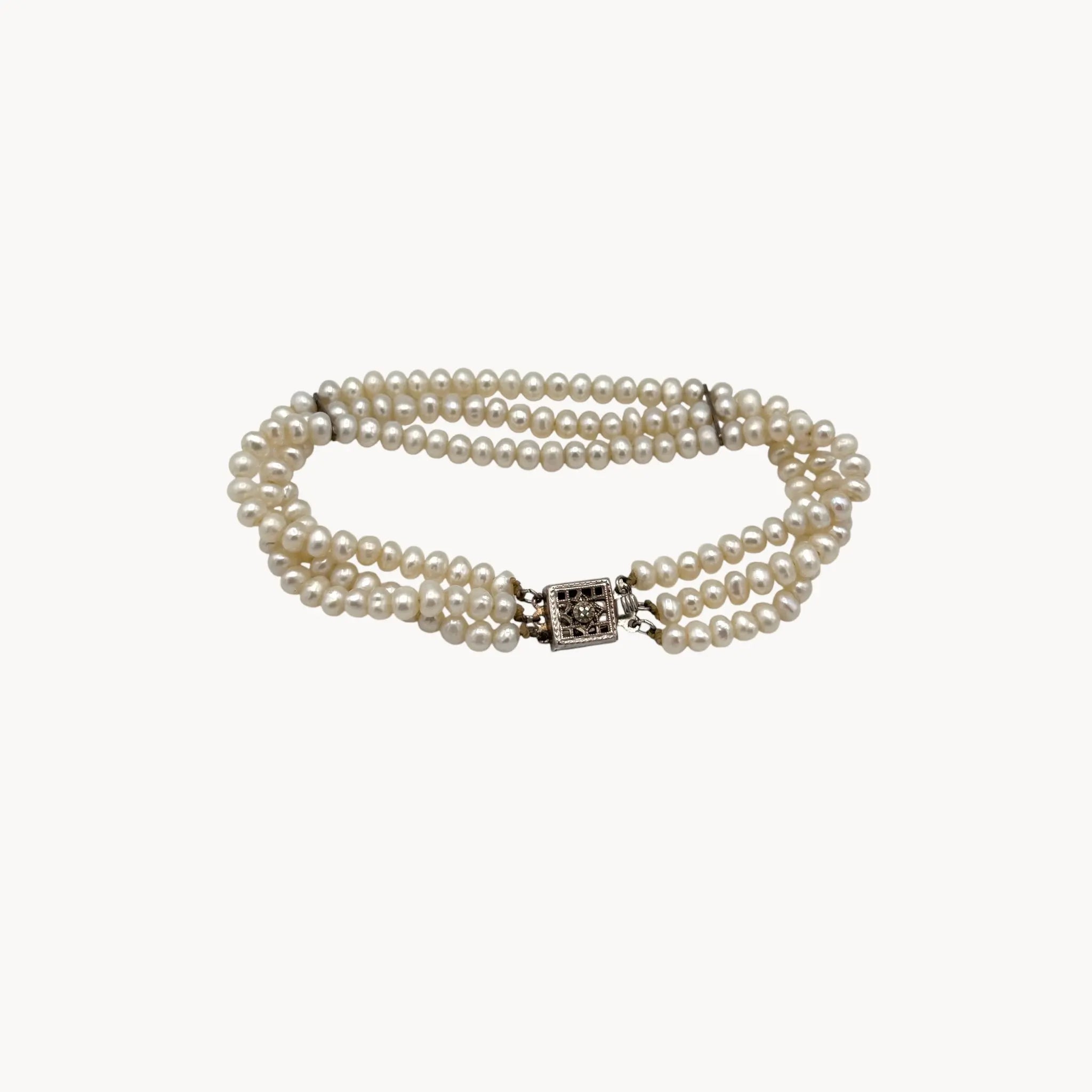 On white background Three row pearl bracelet with silver-tone Art Deco style clasp.