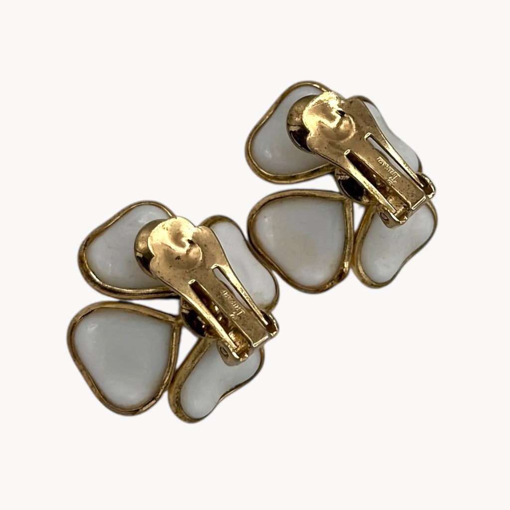 Trifari mark view of Vintage Trifari gold-tone dogwood flower clip-on earrings with white milk glass petals on white background.