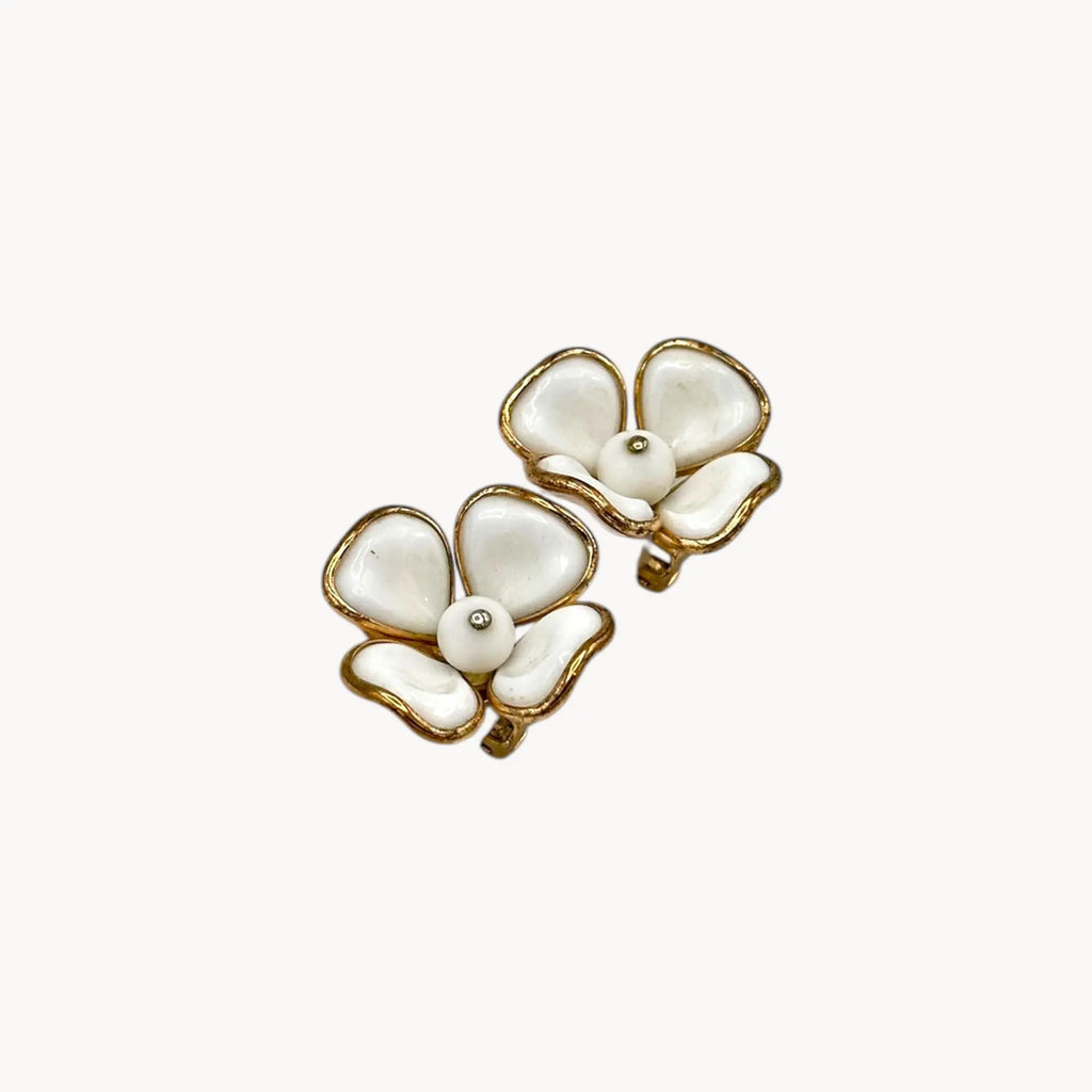 Side view of Vintage Trifari gold-tone dogwood flower clip-on earrings with white milk glass petals on white background.