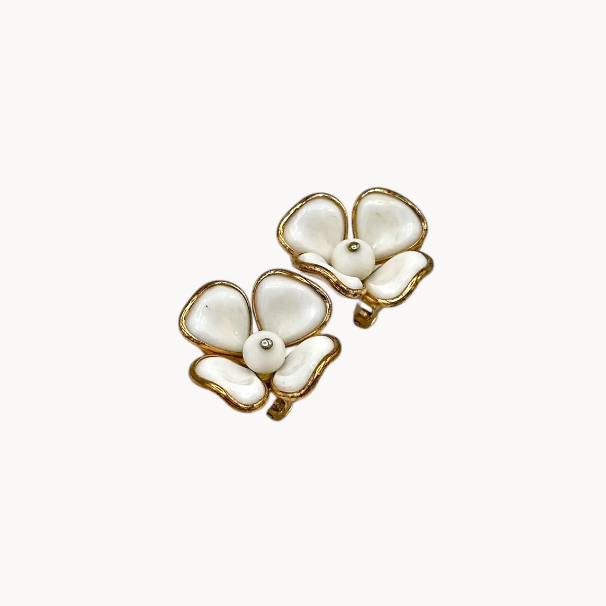 Side view of Vintage Trifari gold-tone dogwood flower clip-on earrings with white milk glass petals on white background.