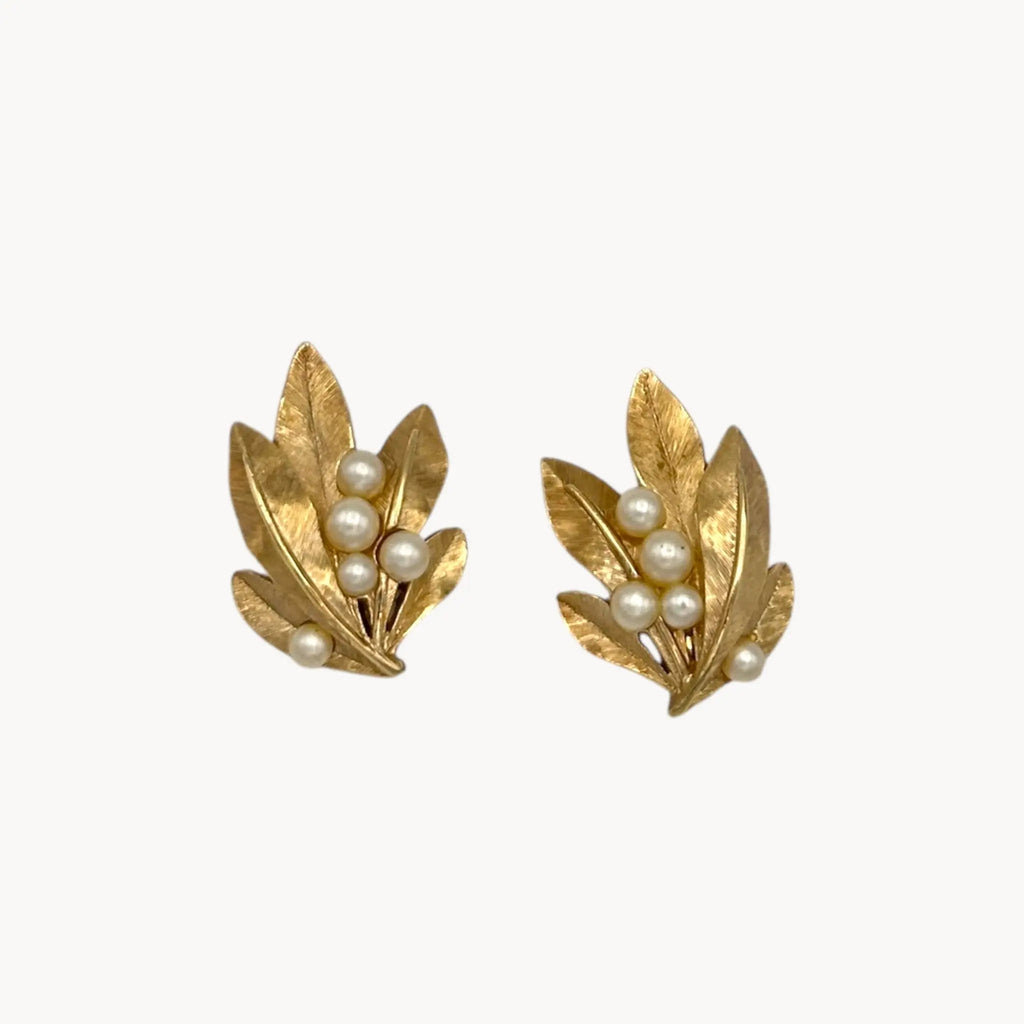 Close up of Vintage Trifari gold leaf clip-on earrings with faux pearls, 1960s jewelry on white background.