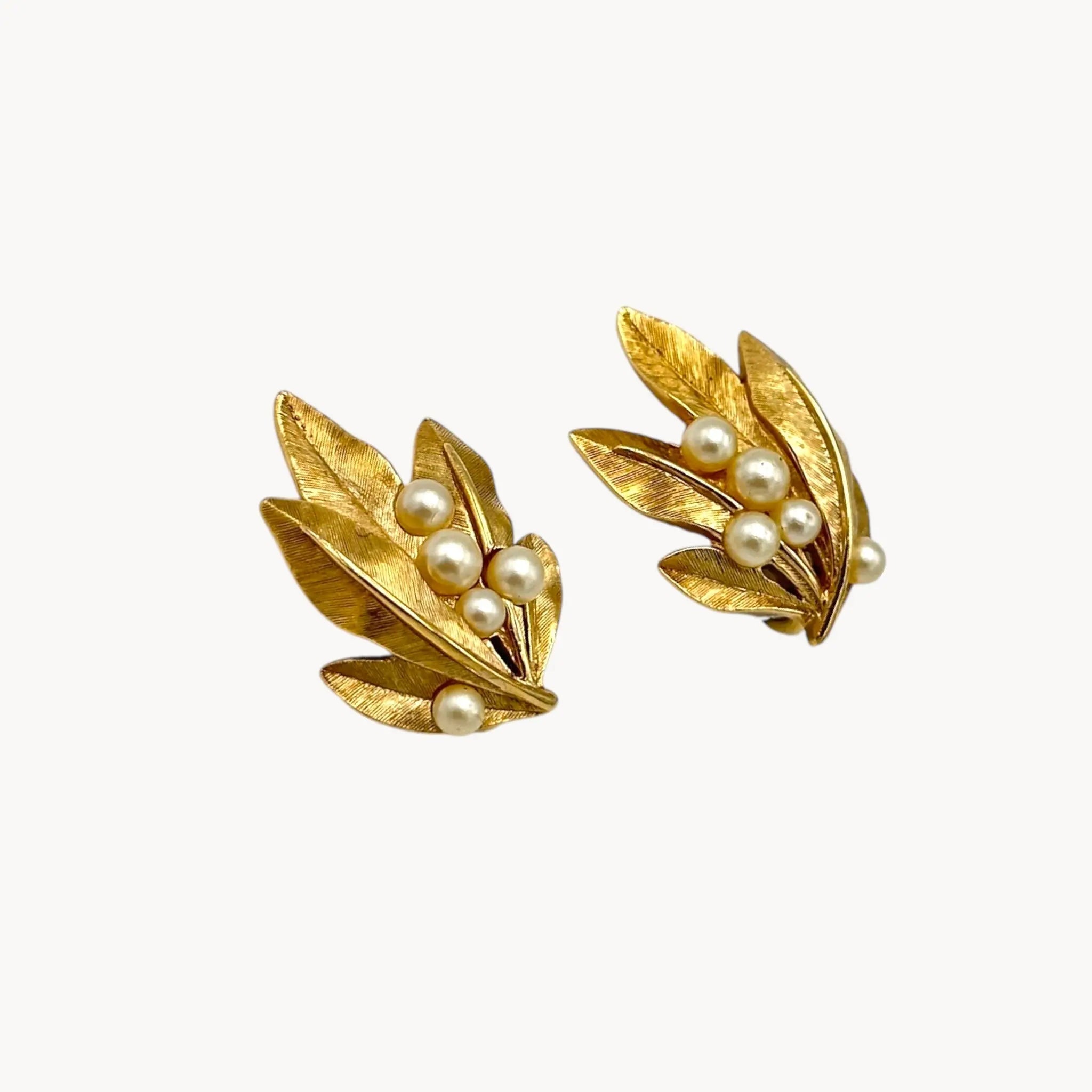 Side view of Vintage Trifari gold leaf clip-on earrings with faux pearls, 1960s jewelry on white background.