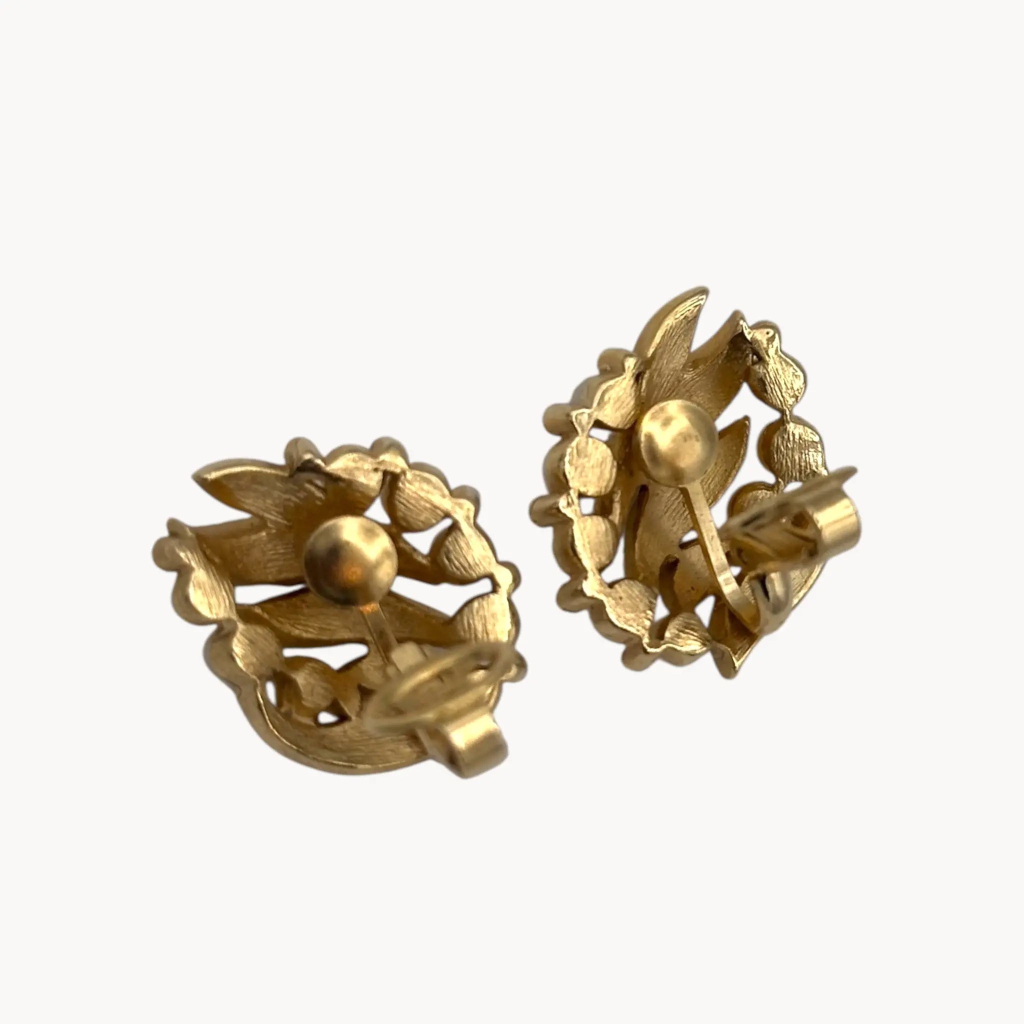 Back view with clips up of Vintage Trifari gold floral clip-on earrings with faux pearls and rhinestones, 1960s jewelry on white background.