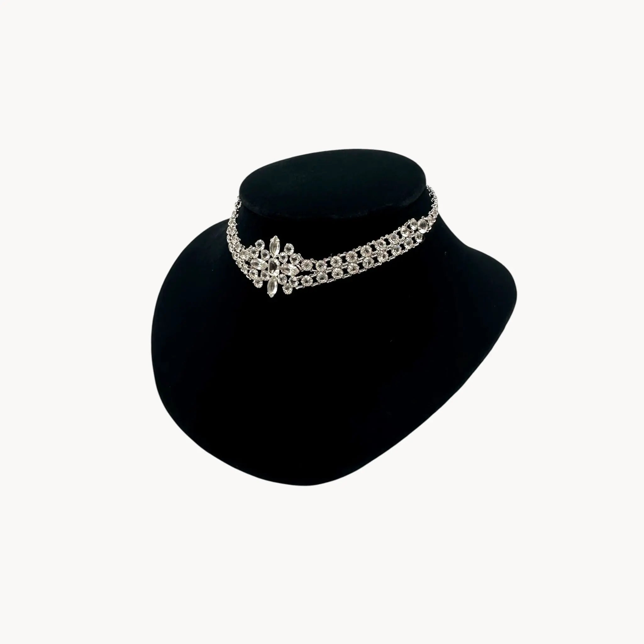 Silver necklace on a black mannequin bust against a white background