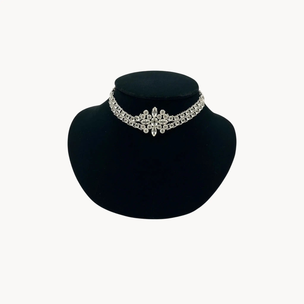 Silver necklace on a black mannequin bust against a white background