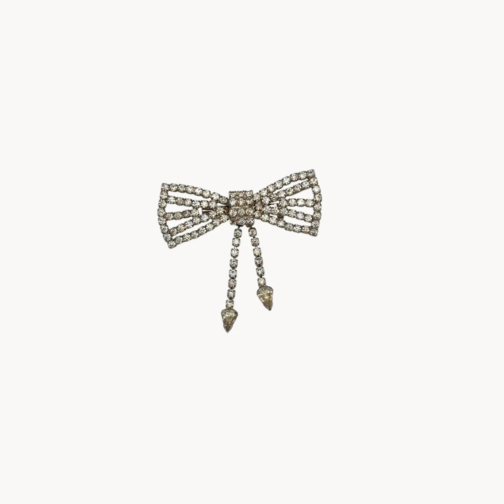 Close up view of Vintage Art Deco style rhinestone bow brooch with dangle drops.