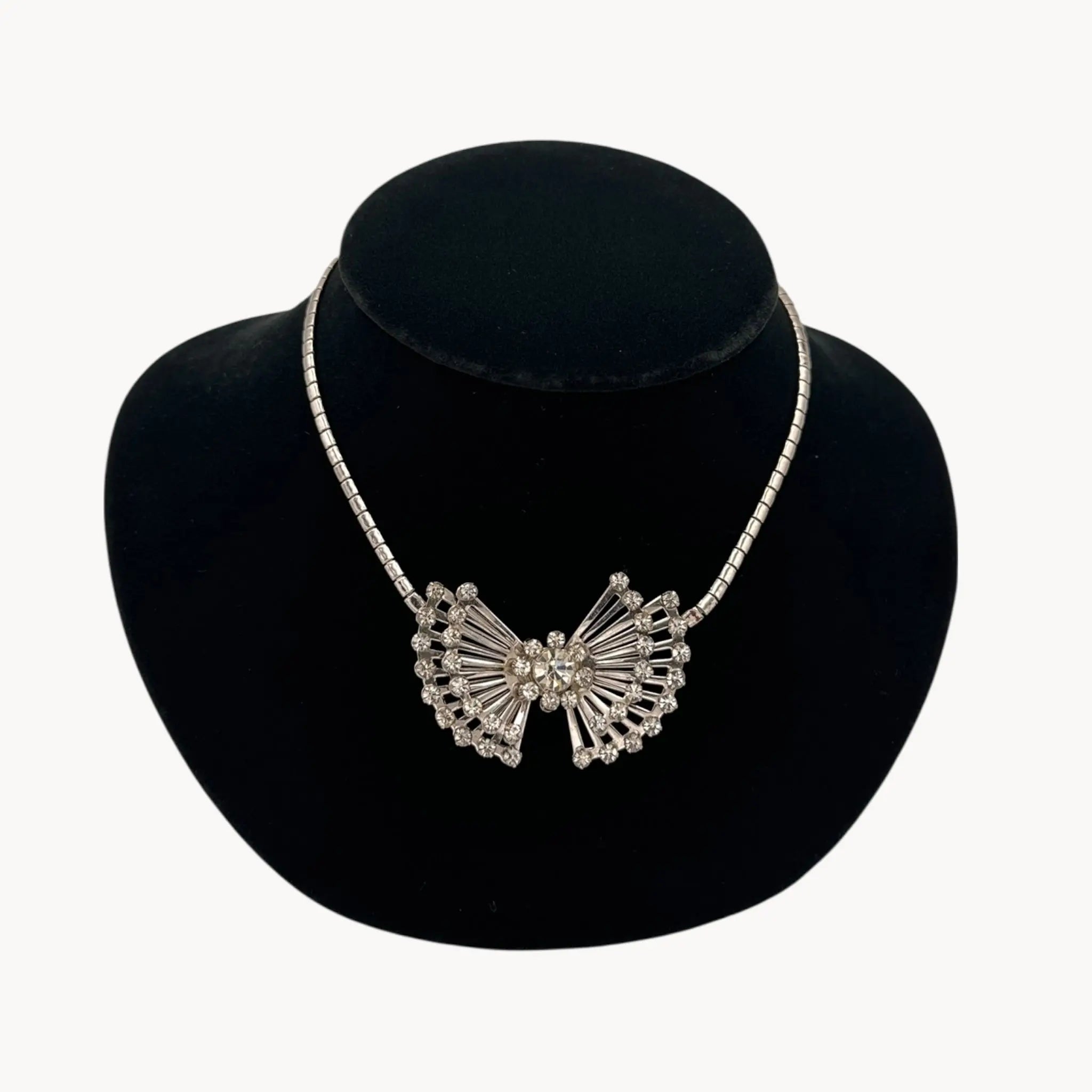 Close up view of Vintage 1950s silver plated rhinestone necklace with statement bow design, mid-century bridal jewelry.