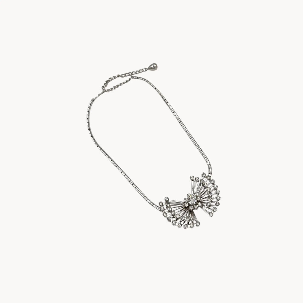 On white background view of Vintage 1950s silver plated rhinestone necklace with statement bow design, mid-century bridal jewelry.