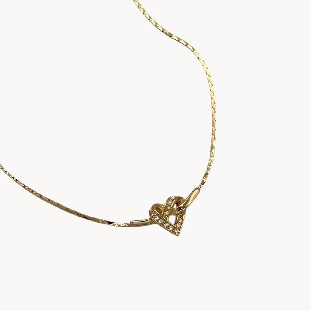 Close up view of pendant of Vintage Christian Dior gold heart pendant necklace with rhinestone detail.