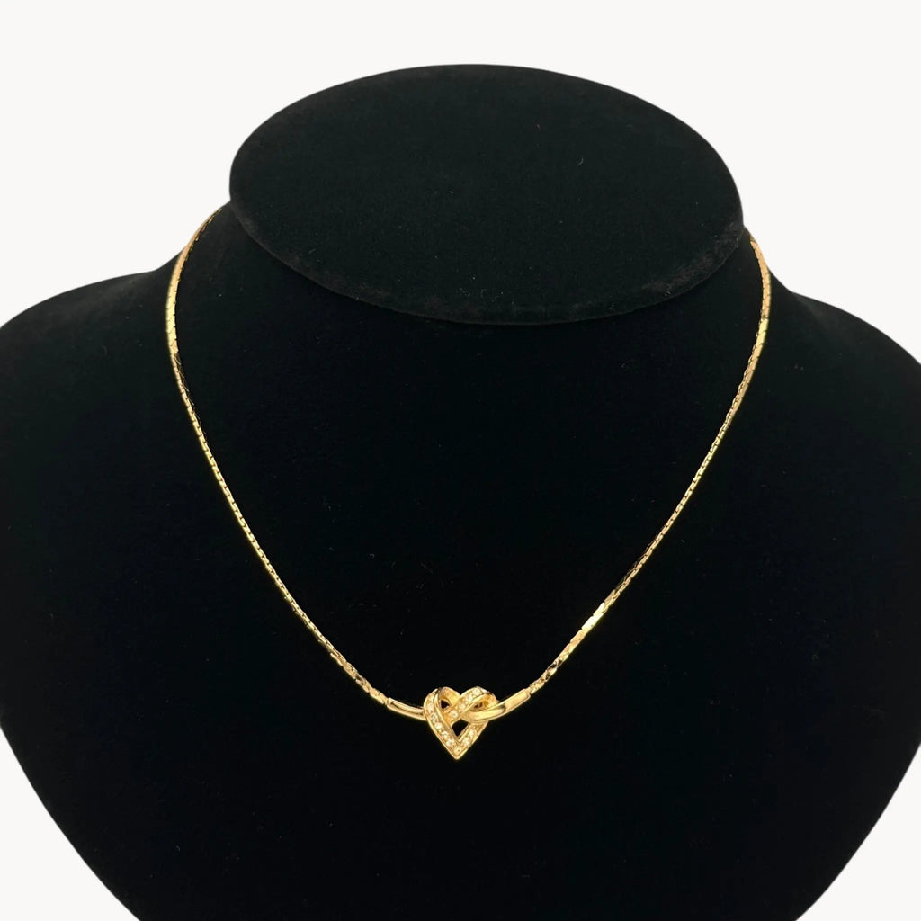 Close up view of Vintage Christian Dior gold heart pendant necklace with rhinestone detail.