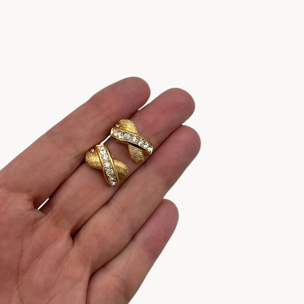 Scale size view of Vintage Christian Dior petite gold-tone clip-on earrings with rhinestone ribbon detail.