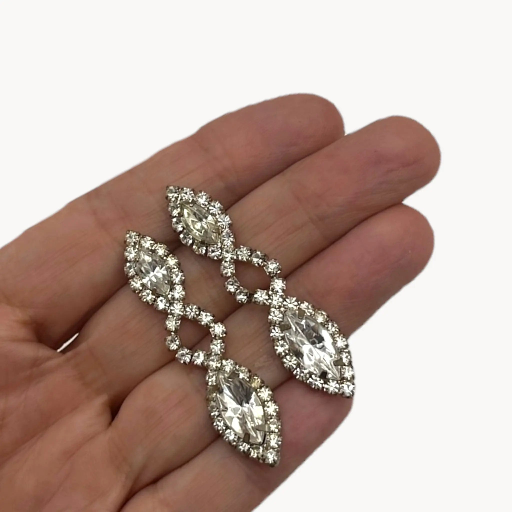 Scale view on hand of Vintage clear rhinestone dangle pierced earrings with marquise stones, bridal jewelry.
