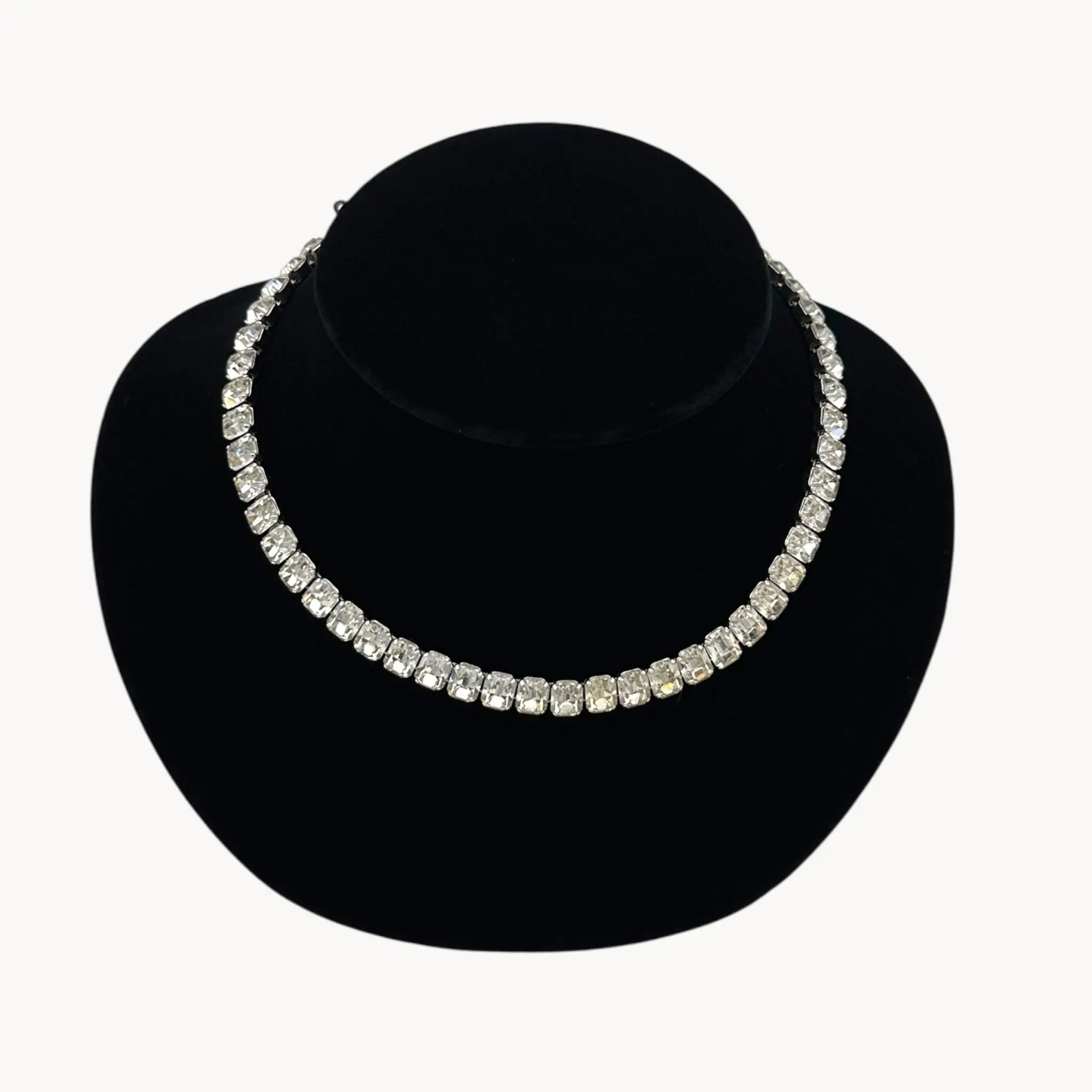 Close up view of Eisenberg Rhinestone vintage necklace black velvet stand against a white background.