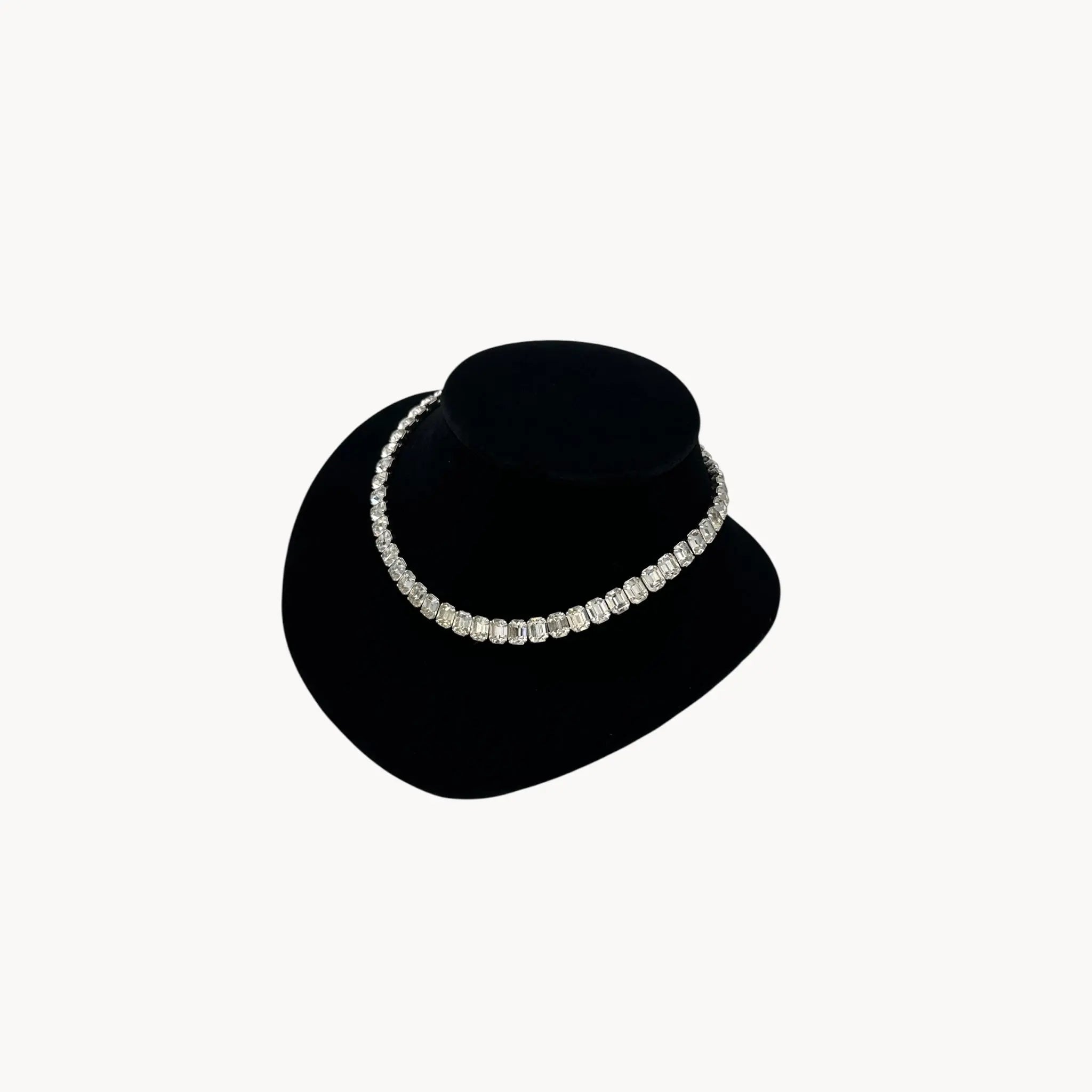 Side view of Eisenberg Rhinestone vintage necklace black velvet stand against a white background.